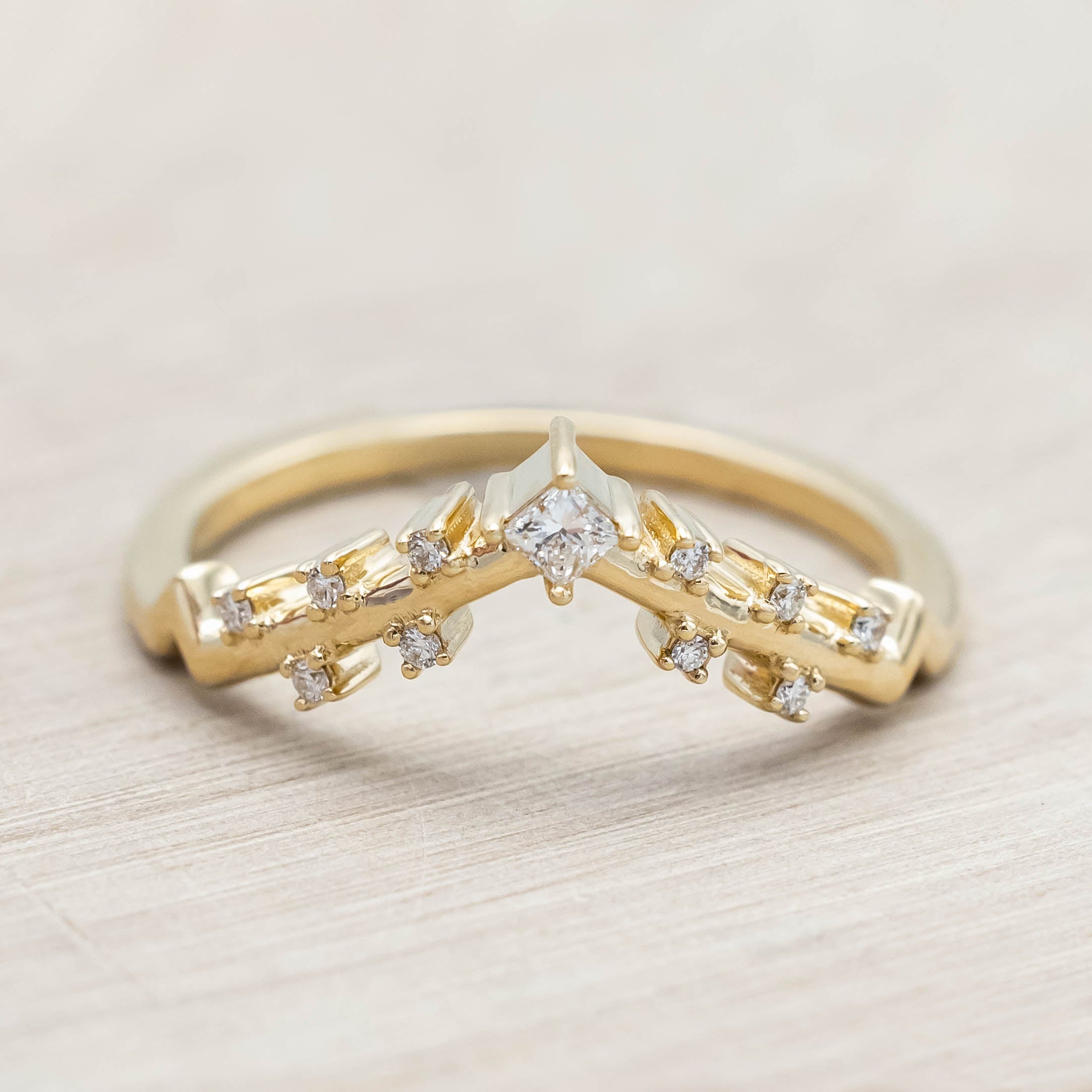 Gold ring with diamonds on a light wooden background