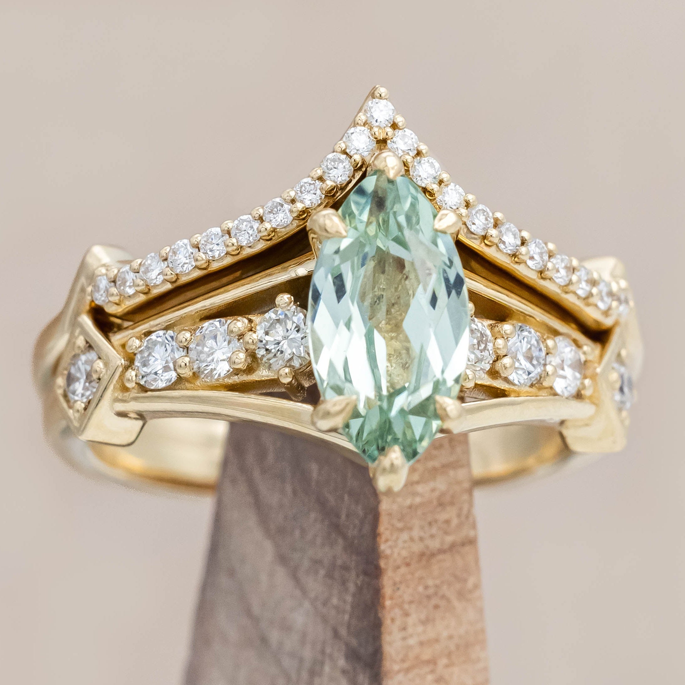 Gold ring with a green sapphire and diamonds on a beige background