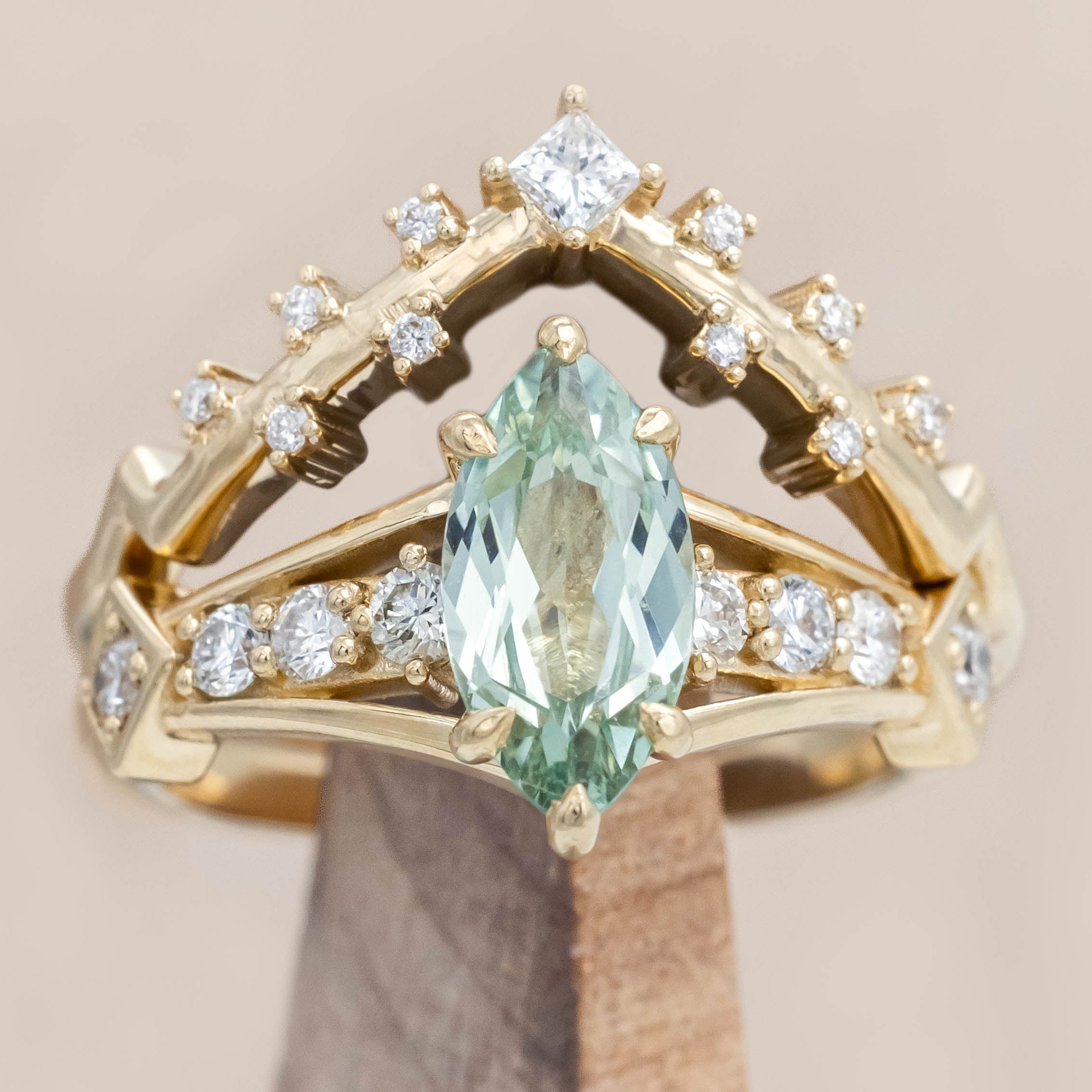Gold ring with a green sapphire and diamonds on a beige background