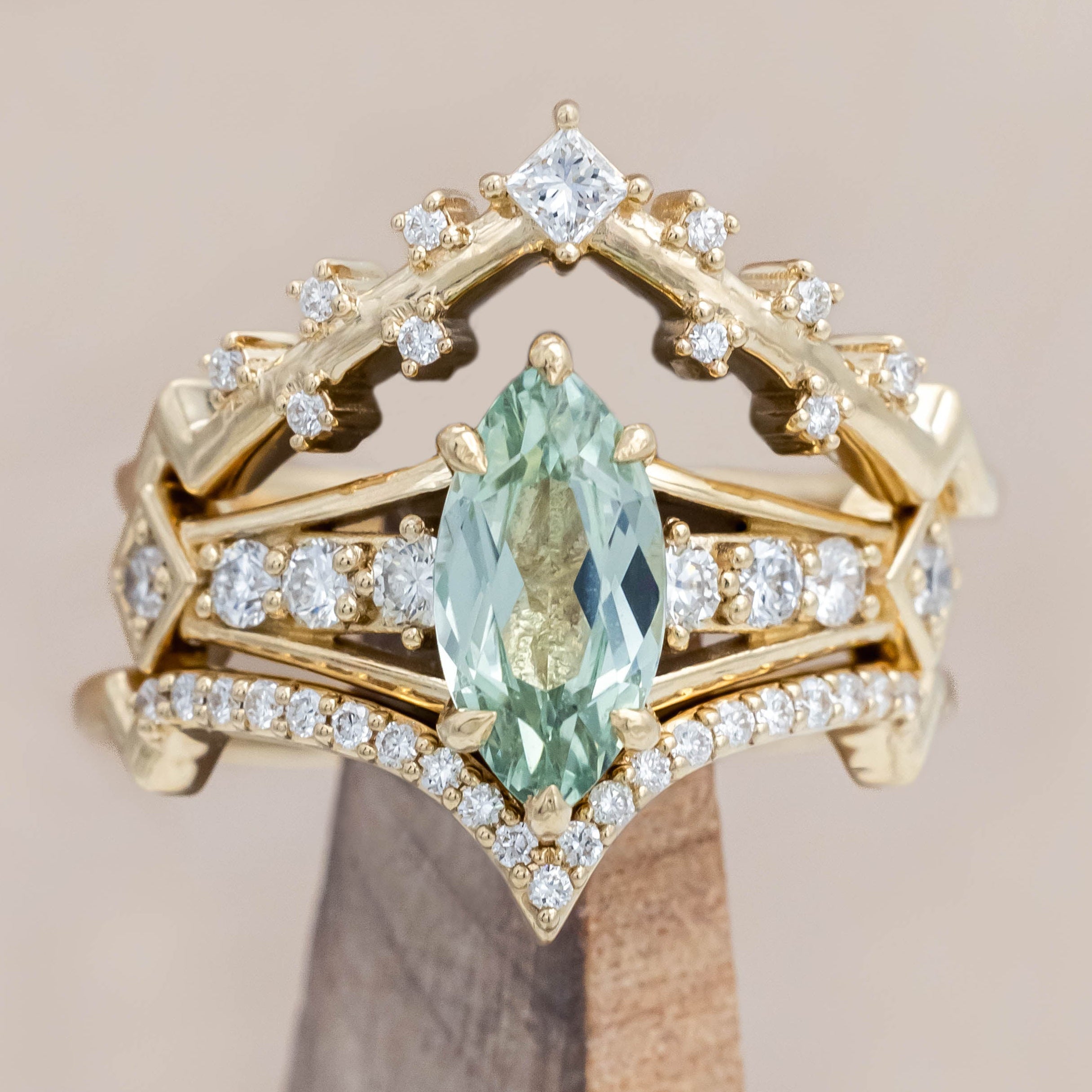Gold ring with a green sapphire and diamonds on a beige background