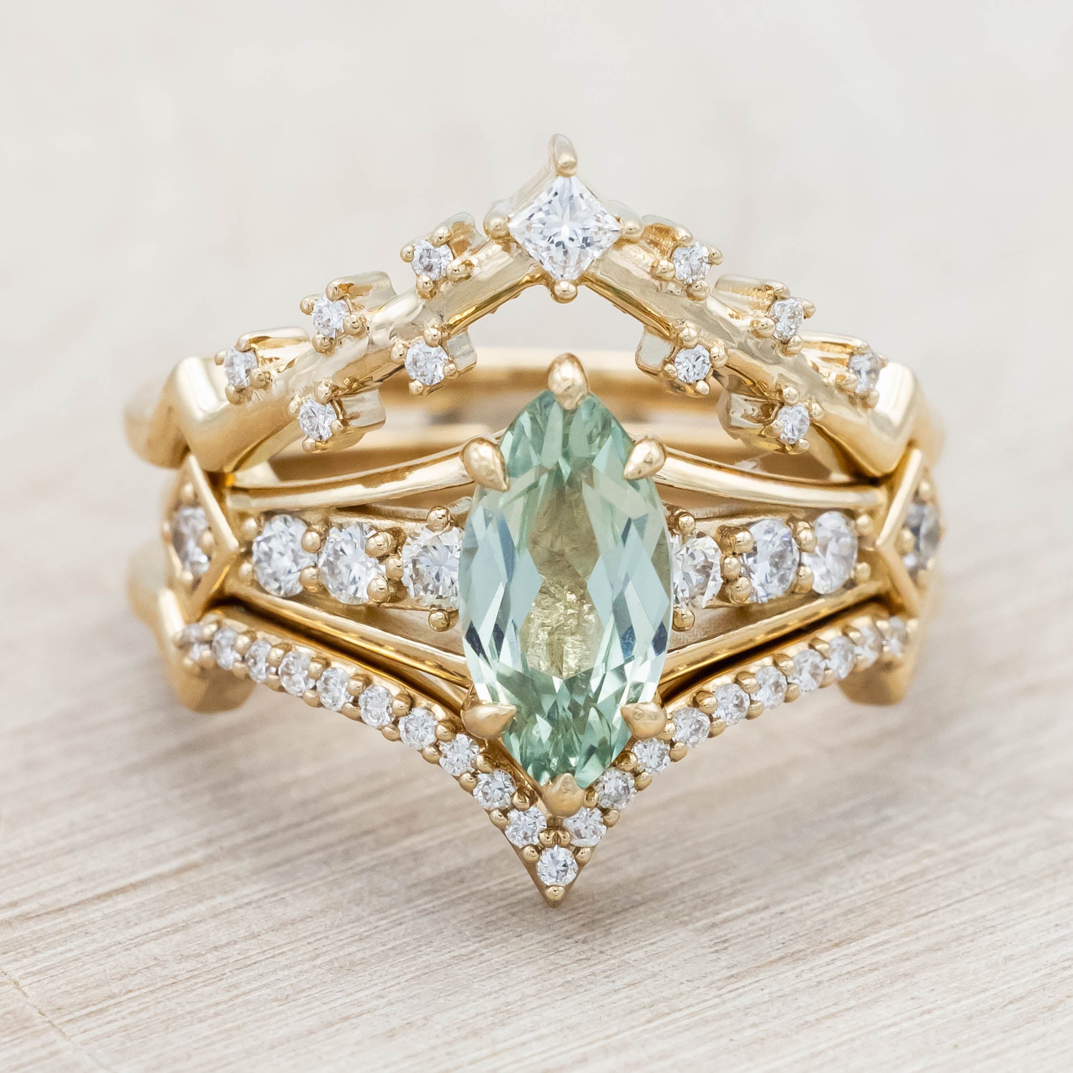 Gold ring with a green sapphire and diamonds on a beige background