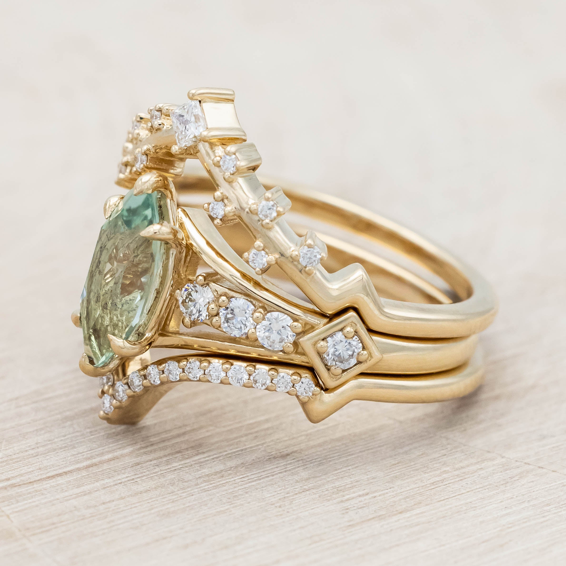Gold ring with a green sapphire and diamonds on a beige background