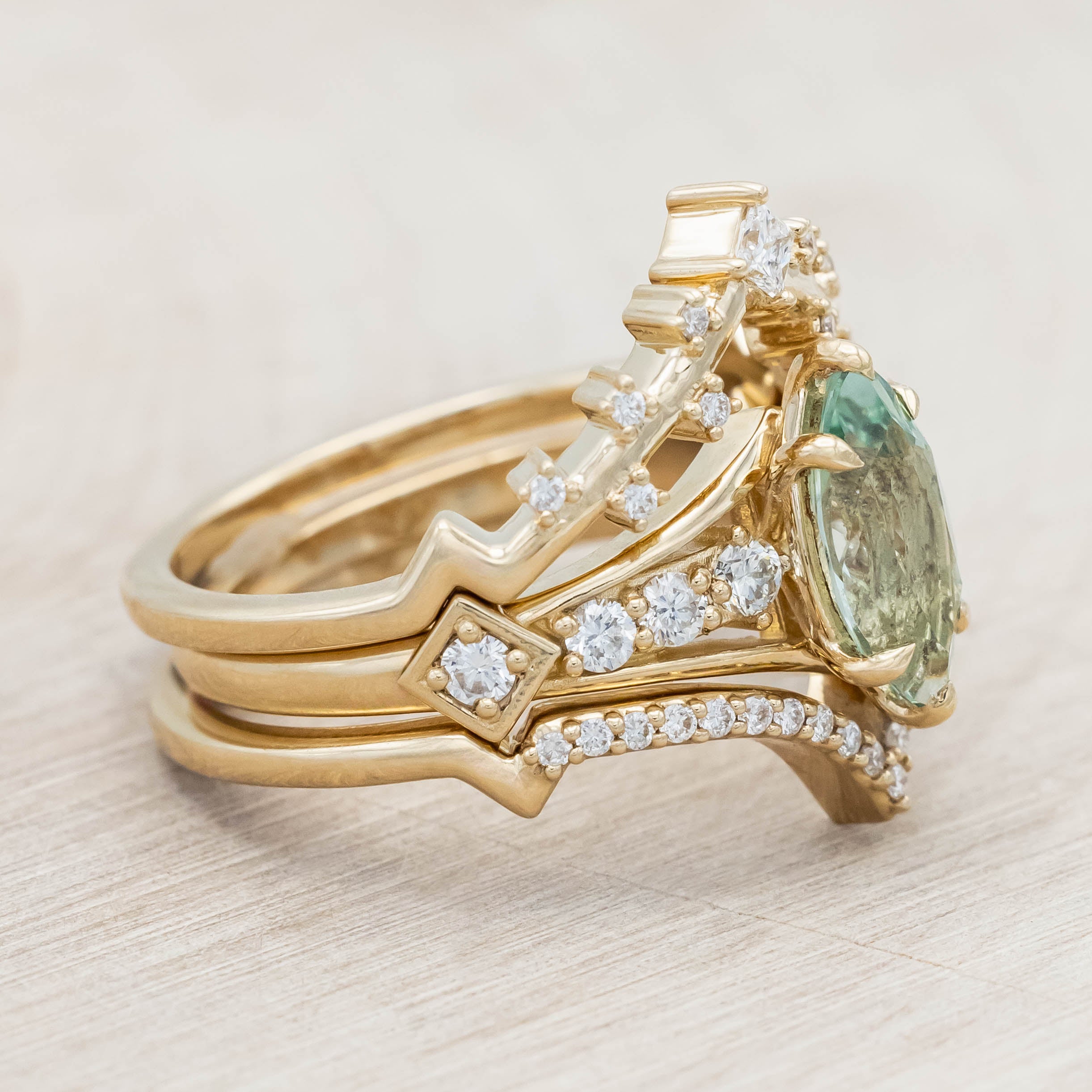 Gold ring with a green sapphire and diamonds on a beige background