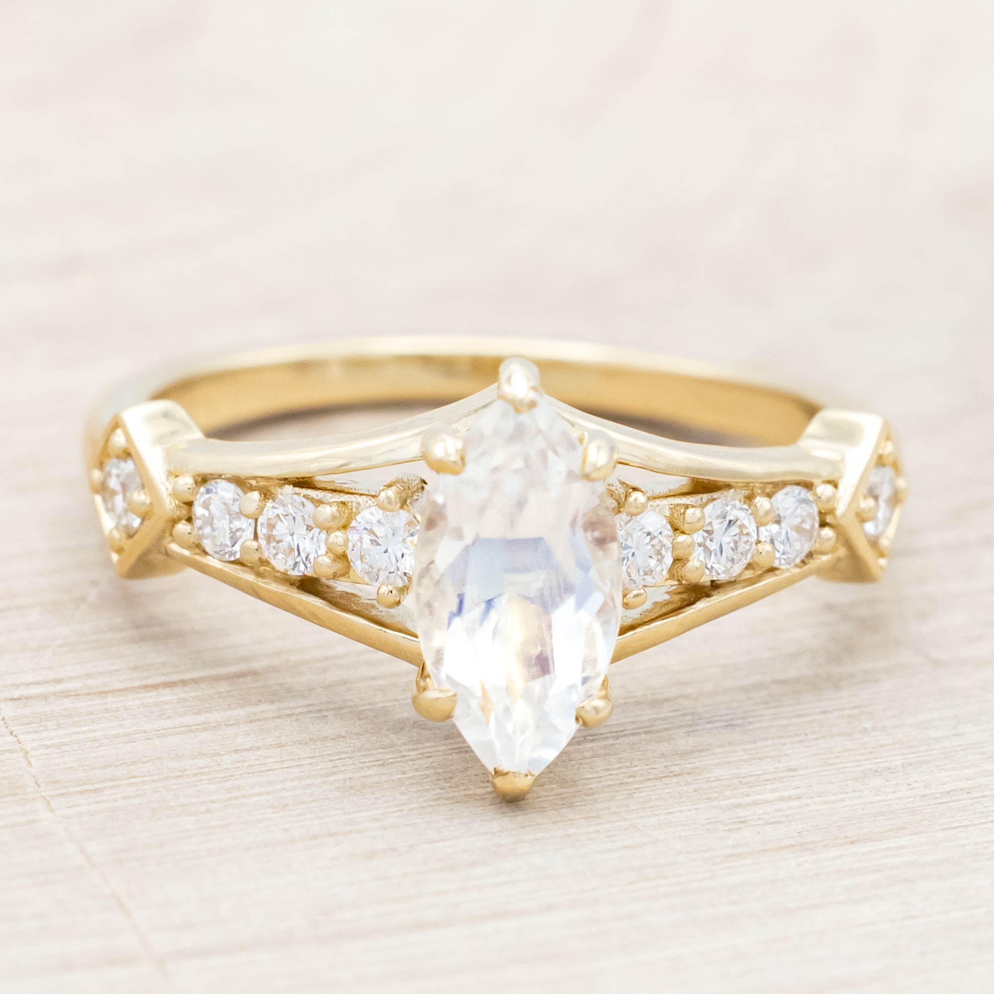 Yellow gold ring with a moonstone and smaller diamonds on a beige background