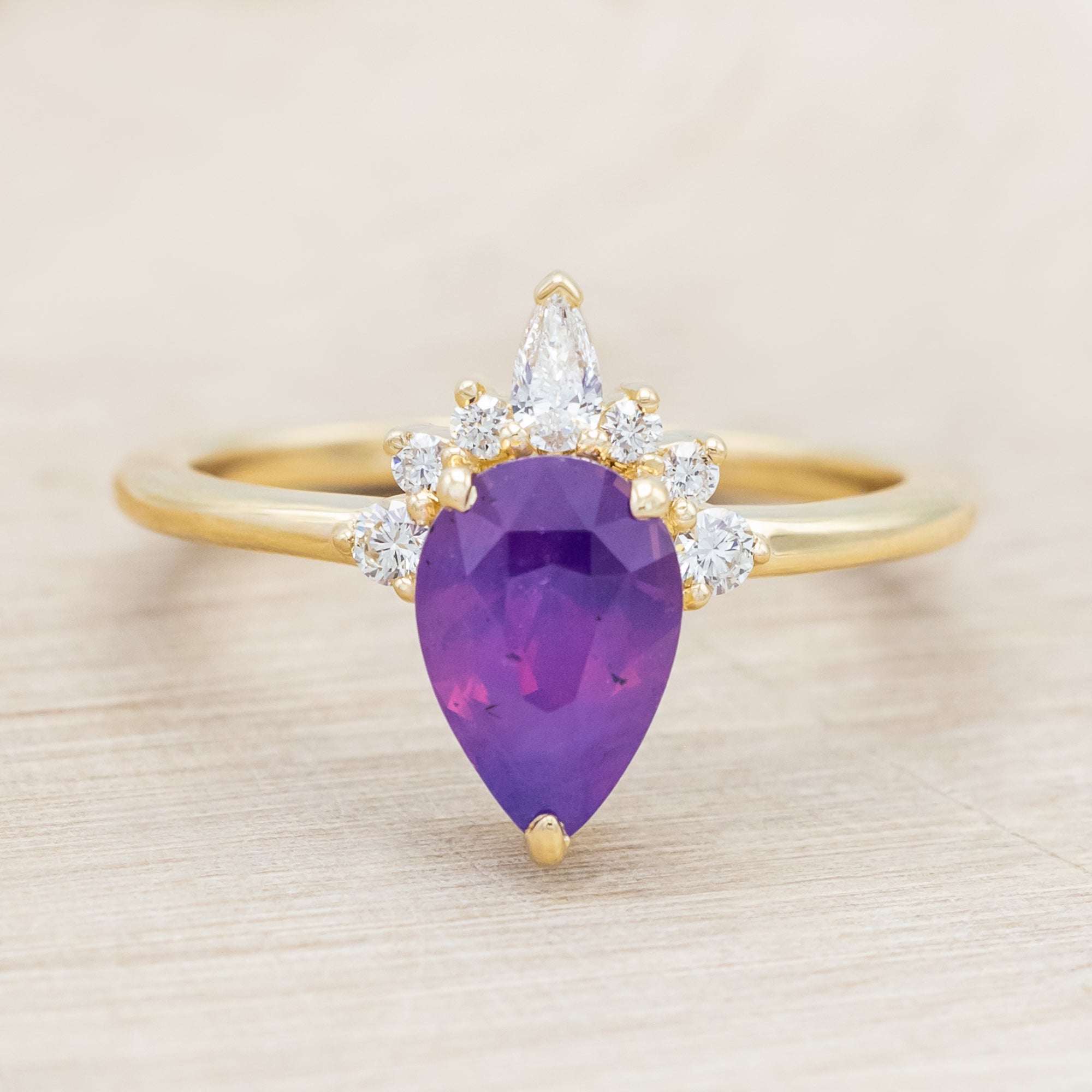 14K gold ring with a pear Sri Lankan sapphire on a beige background