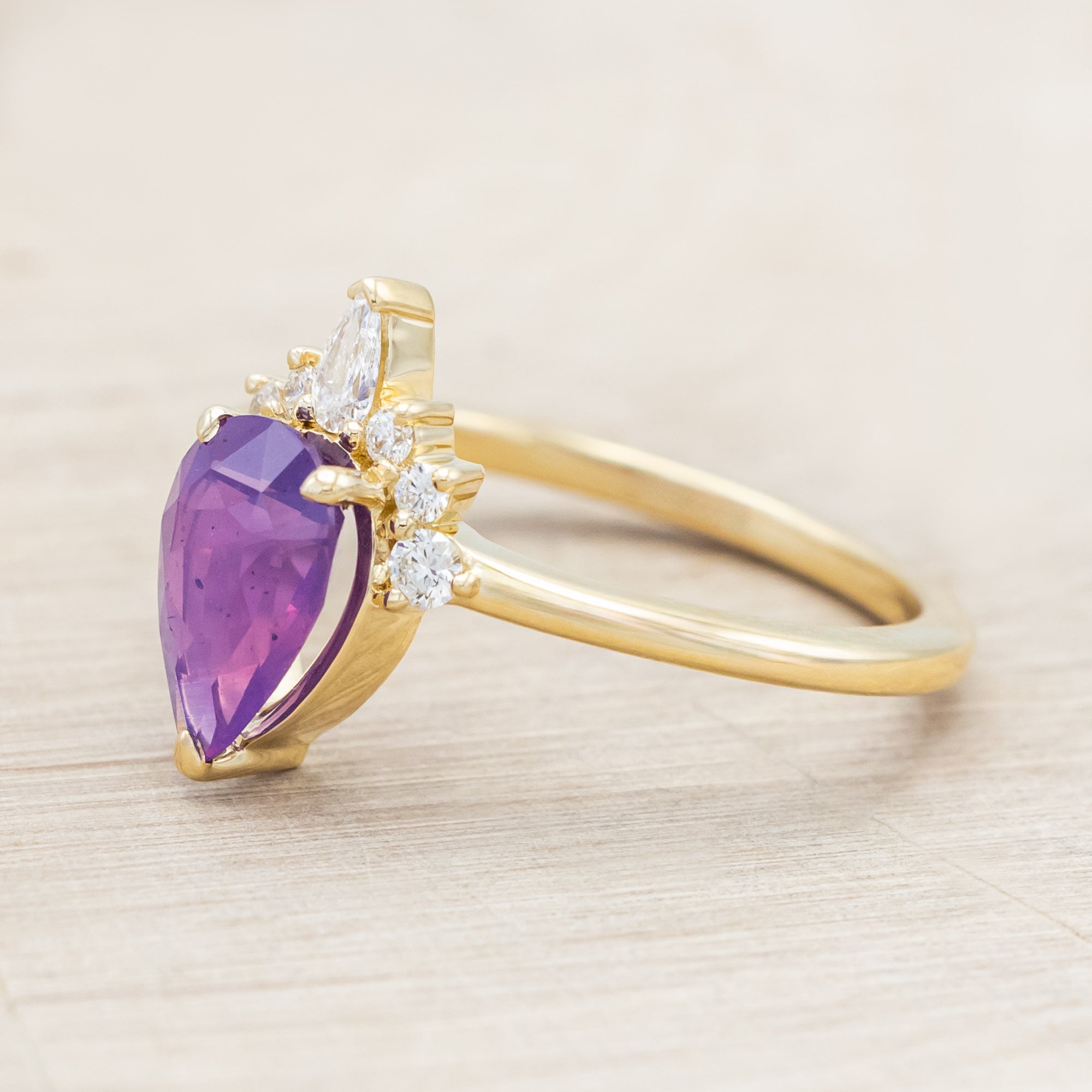 14K gold ring with a pear Sri Lankan sapphire on a beige background