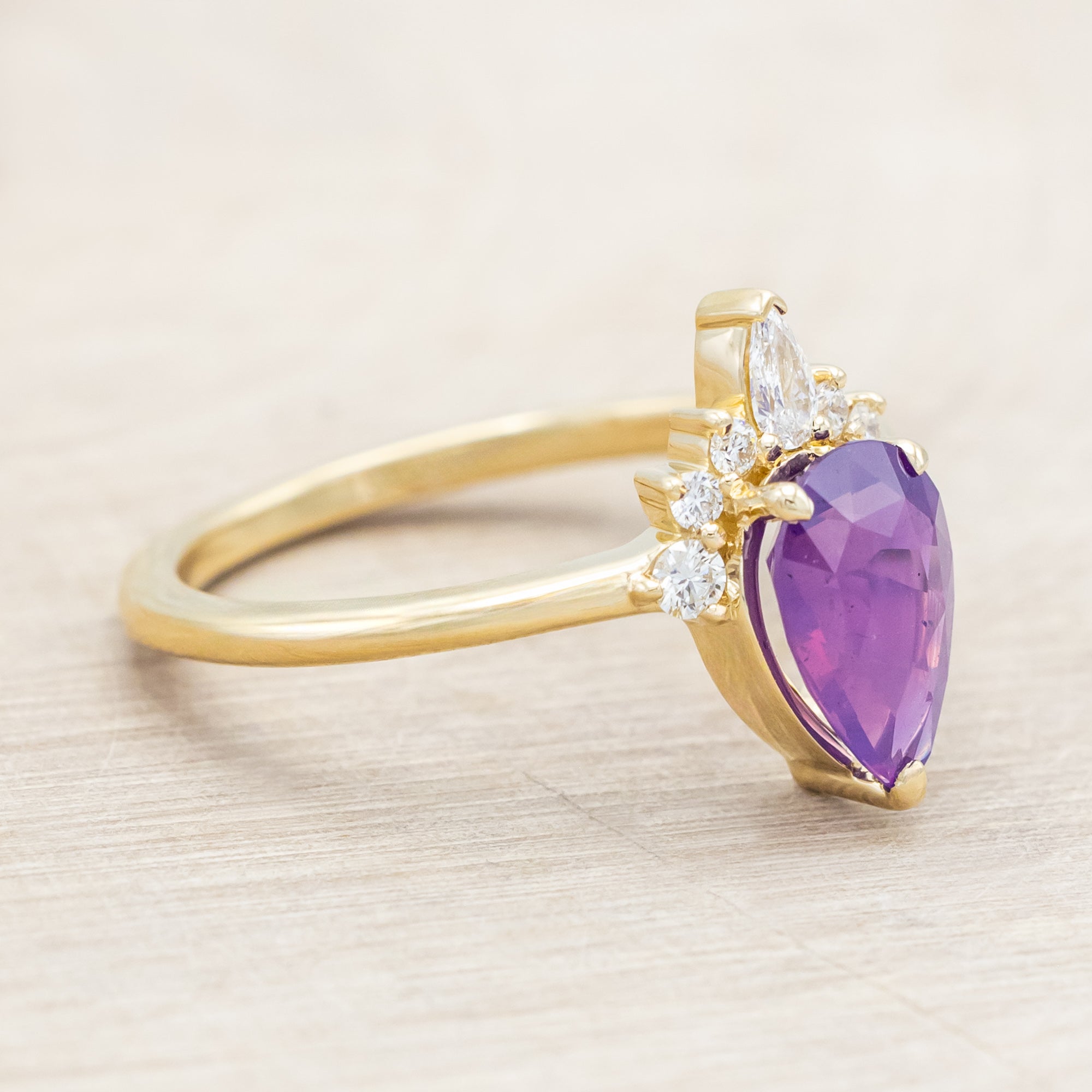 14K gold ring with a pear Sri Lankan sapphire on a beige background