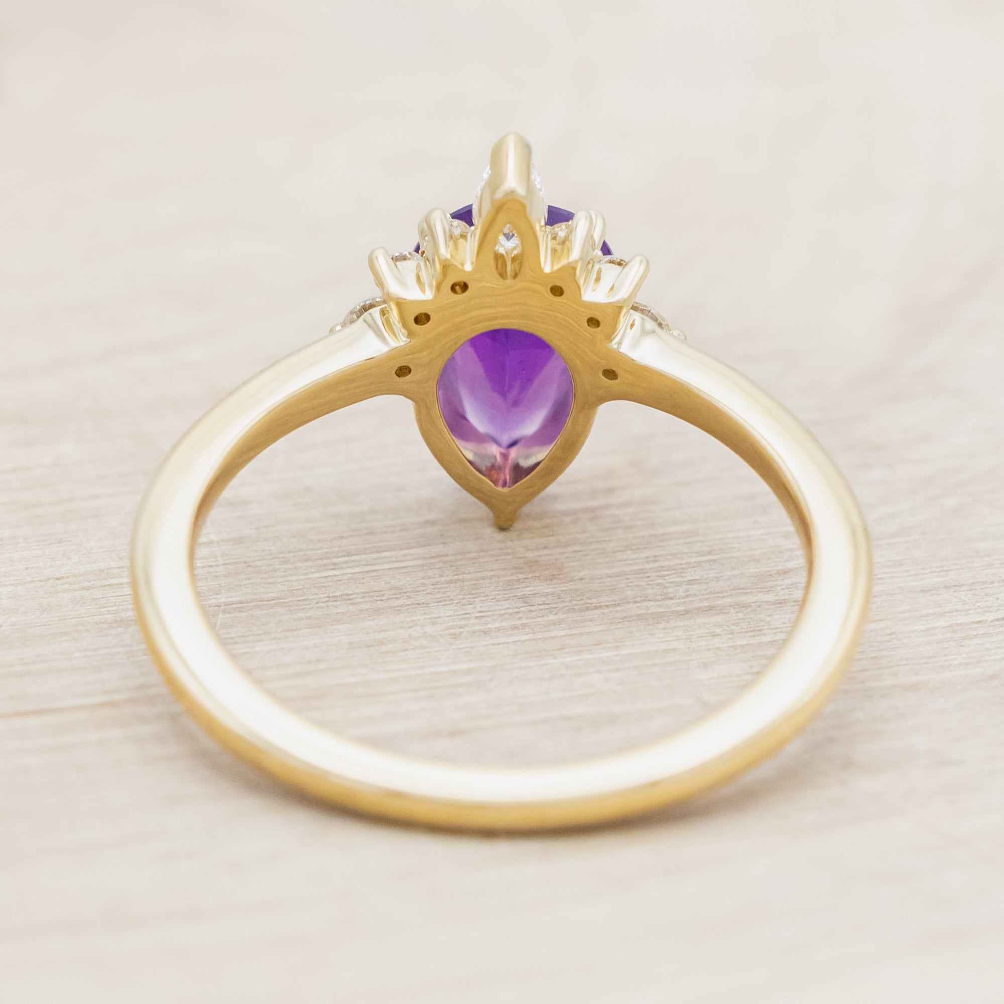 14K gold ring with a pear Sri Lankan sapphire on a beige background