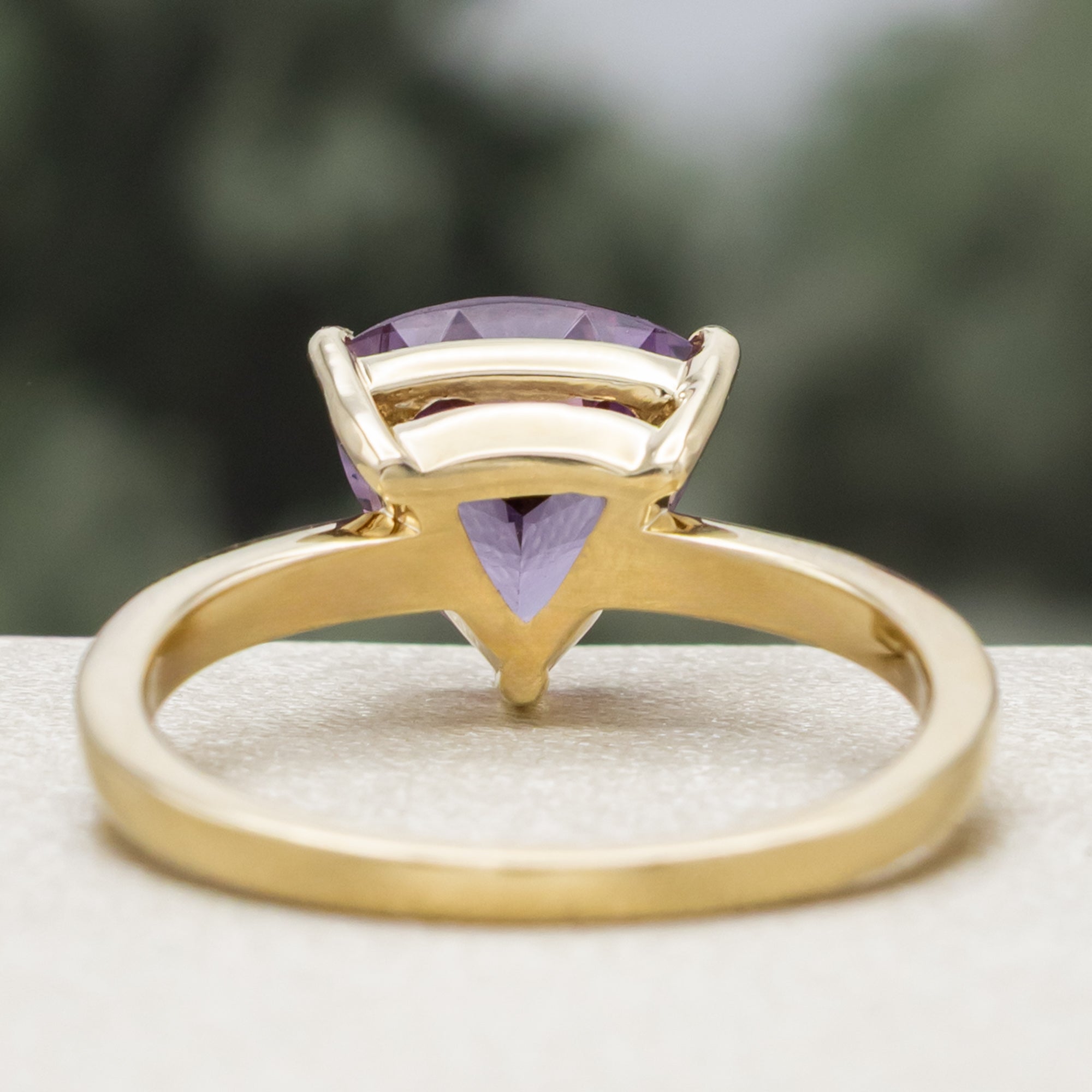 Gold ring with a purple garnet and diamond accents on a blurred background