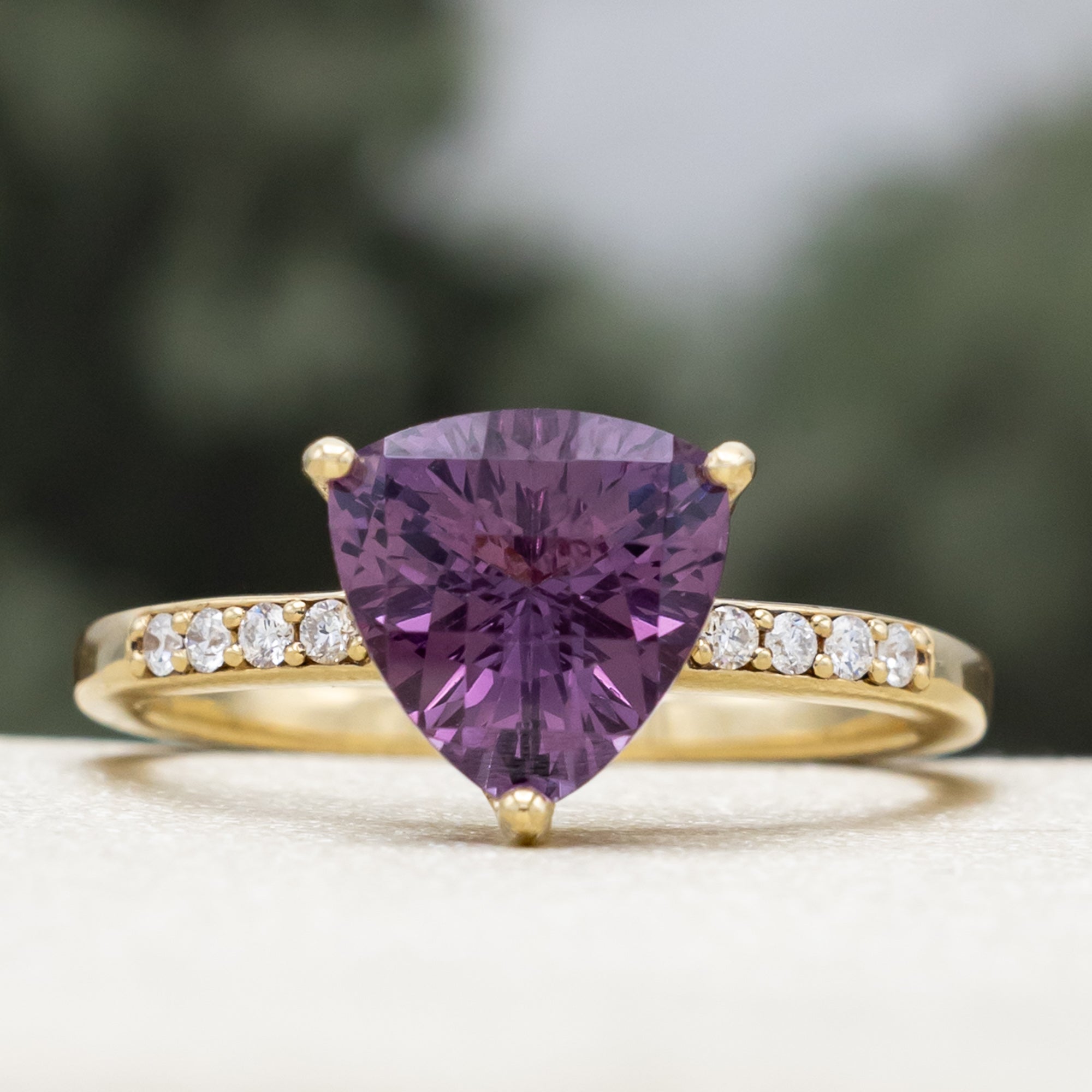 Gold ring with a purple garnet and diamond accents on a blurred background