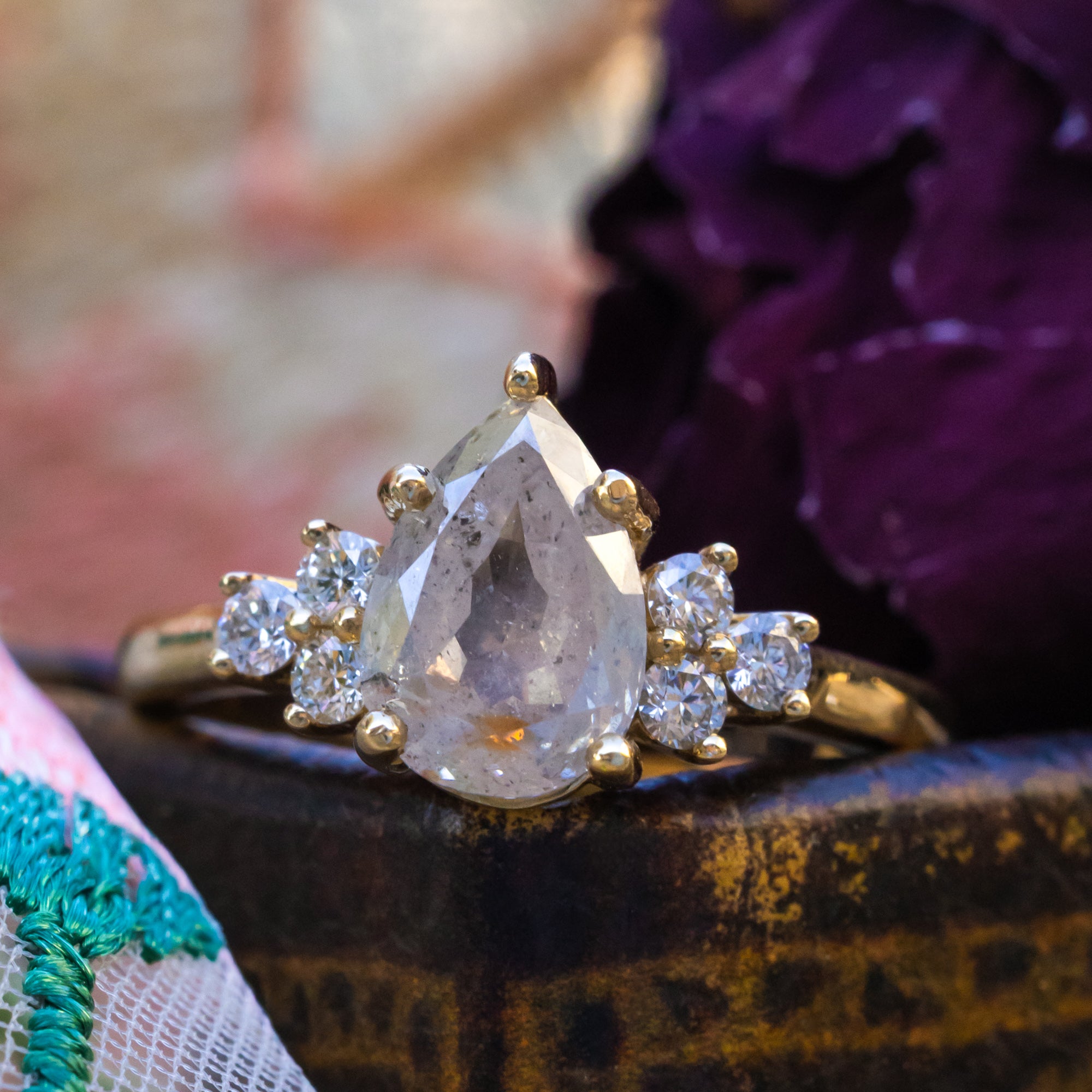 Gold ring with salt & pepper diamond and diamond accents on a decorative surface