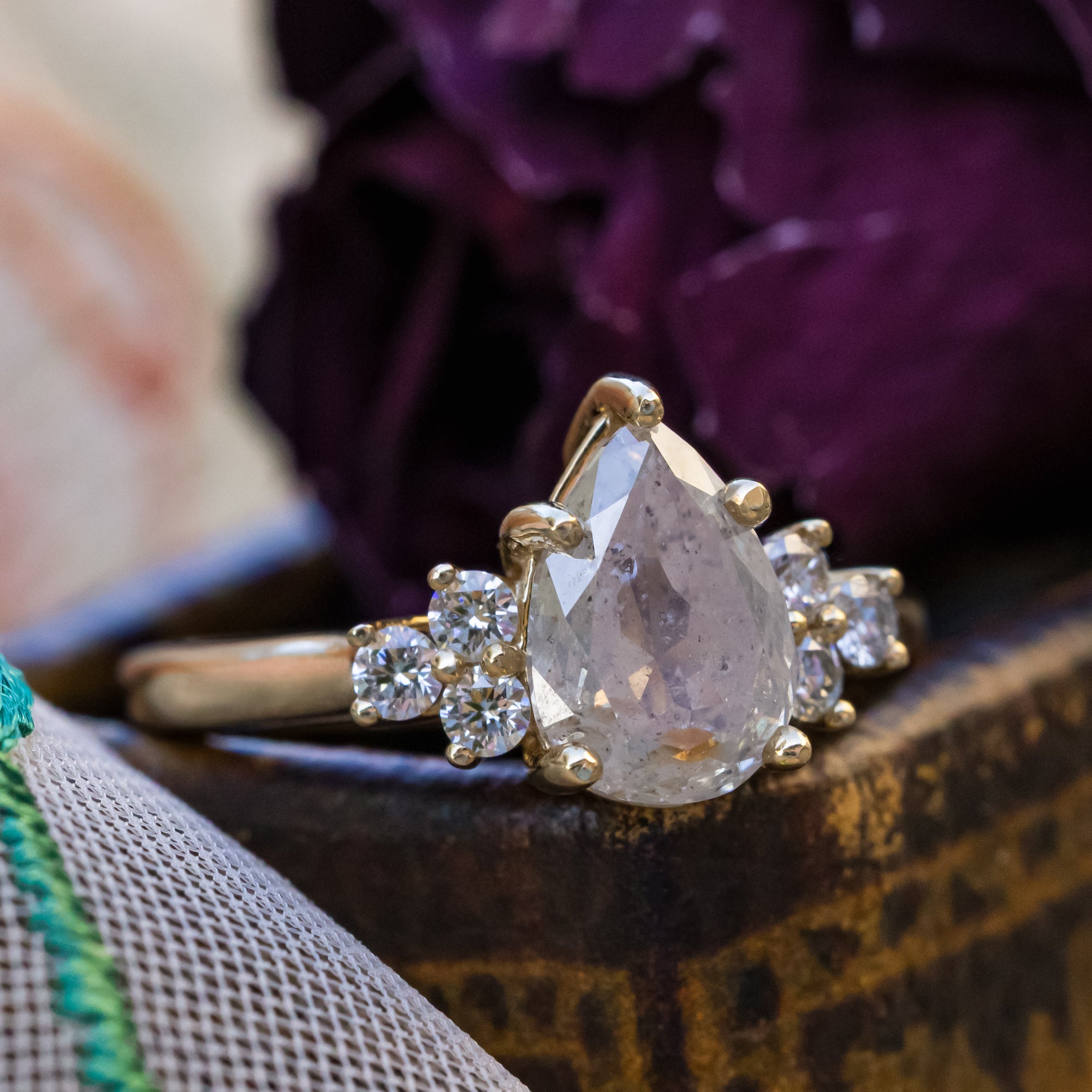 Gold ring with salt & pepper diamond and diamond accents on a decorative surface