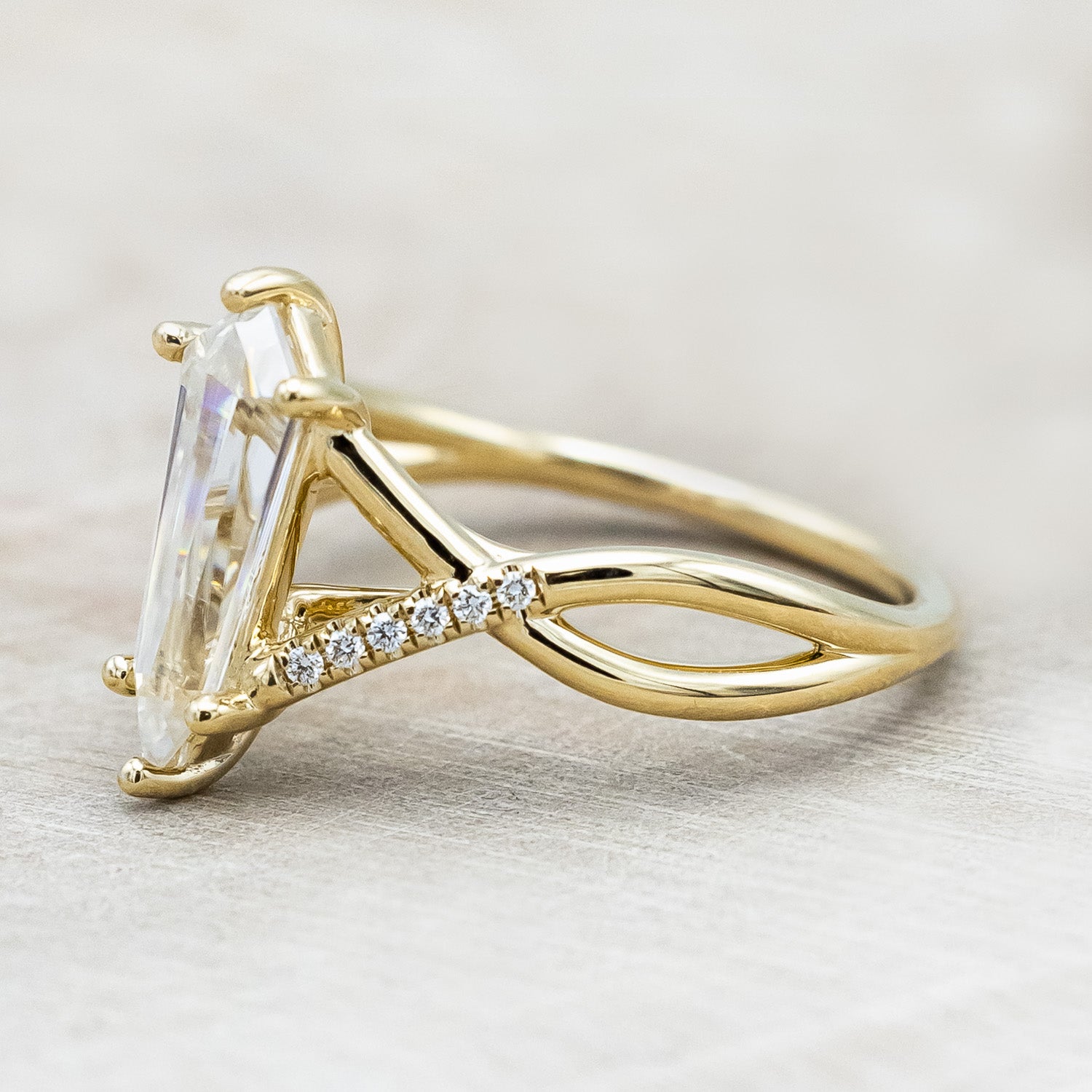 Side view of "Roslyn" - elongated kite cut moissanite women's engagement ring with diamond accents in 14K yellow gold