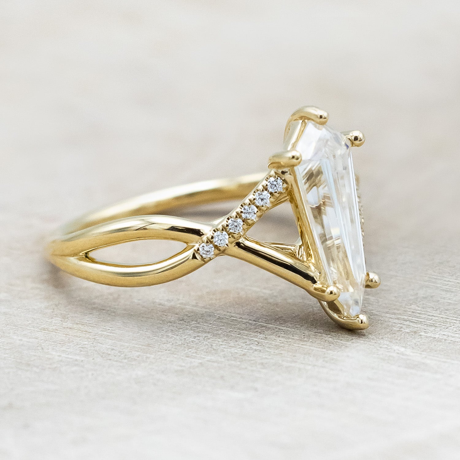 Side view of "Roslyn" - elongated kite cut moissanite women's engagement ring with diamond accents in 14K yellow gold