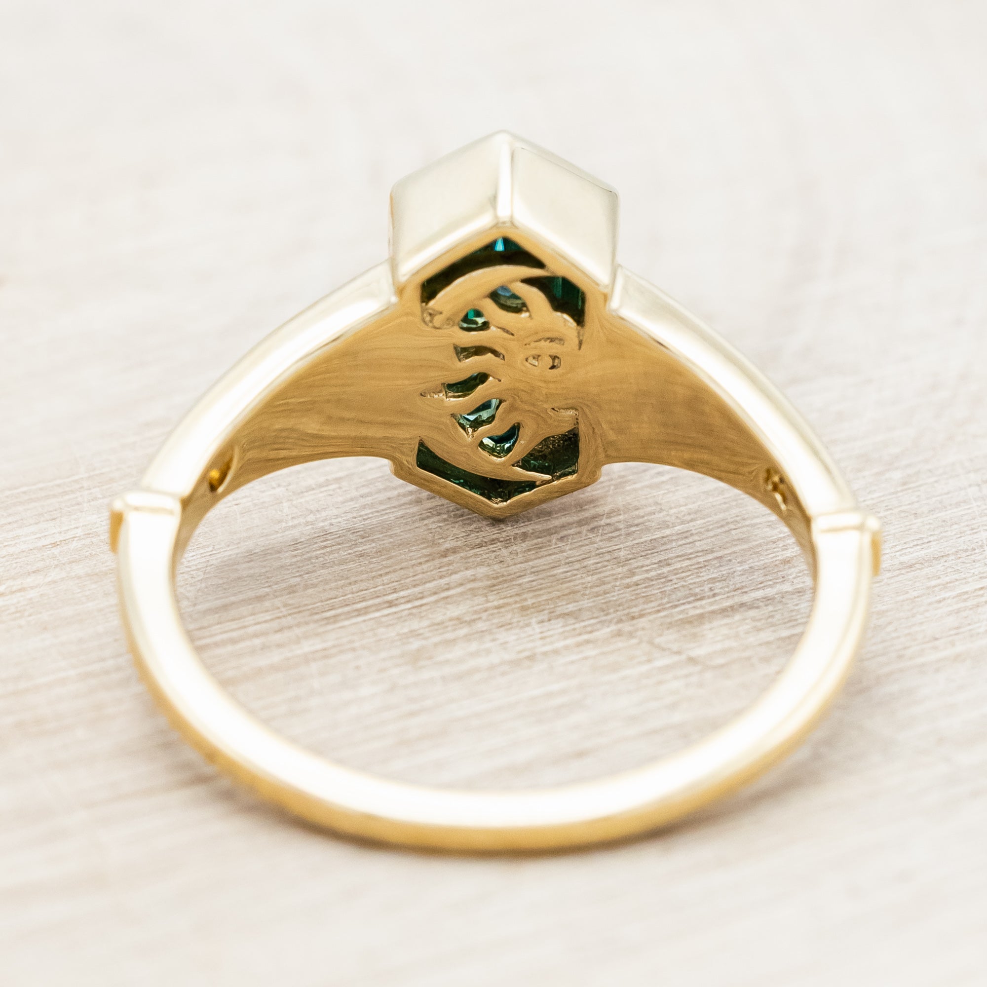 Gold ring with a hexagonal gemstone and sun & moon cutout on a light wooden surface
