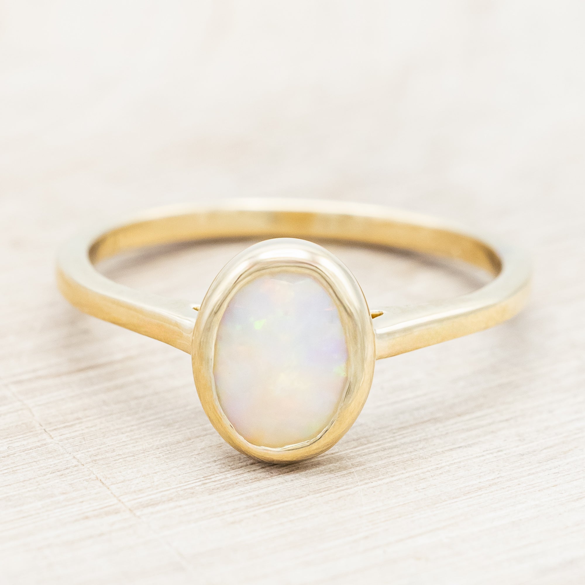 Gold ring with an opal center stone on a neutral background
