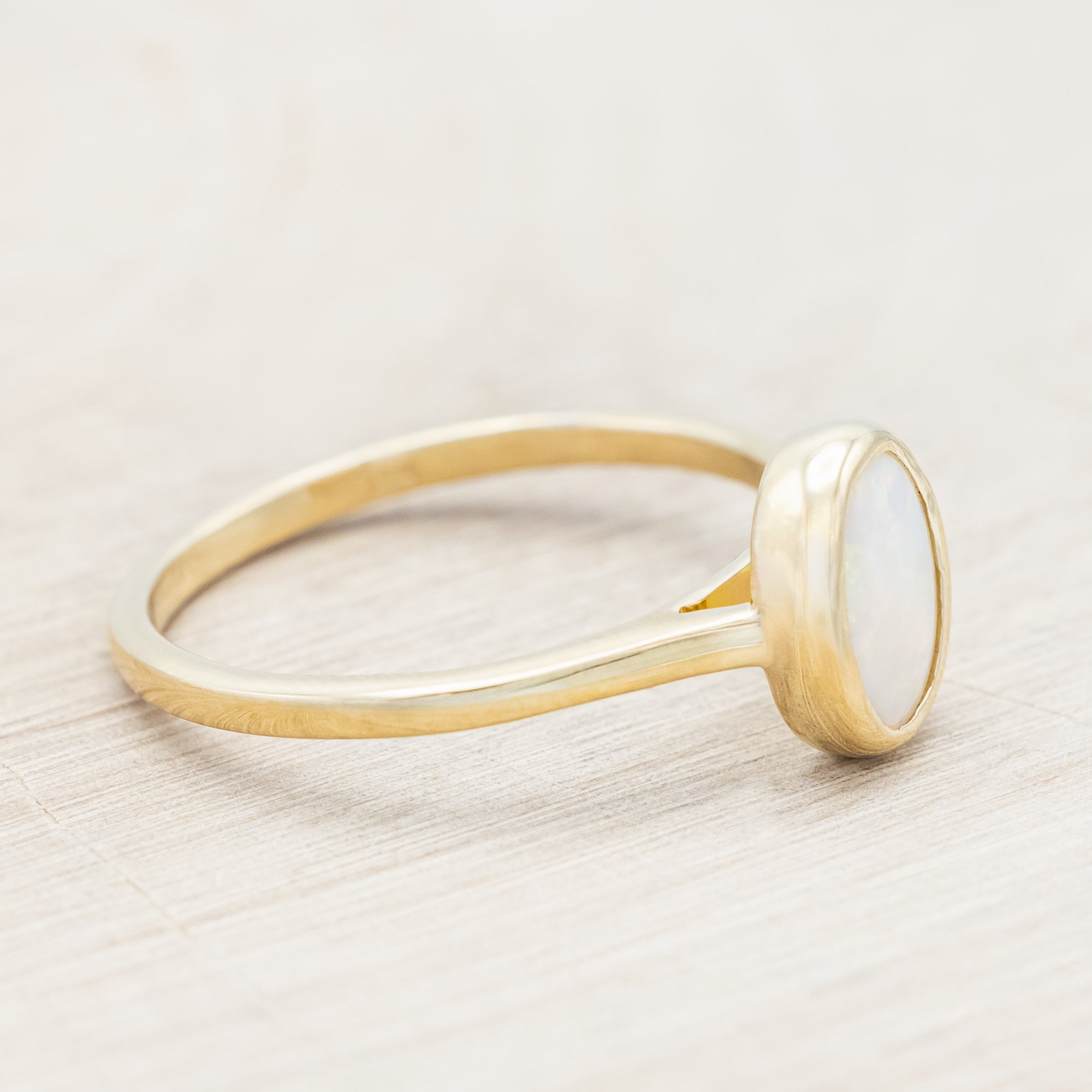Gold ring with an opal center stone on a neutral background