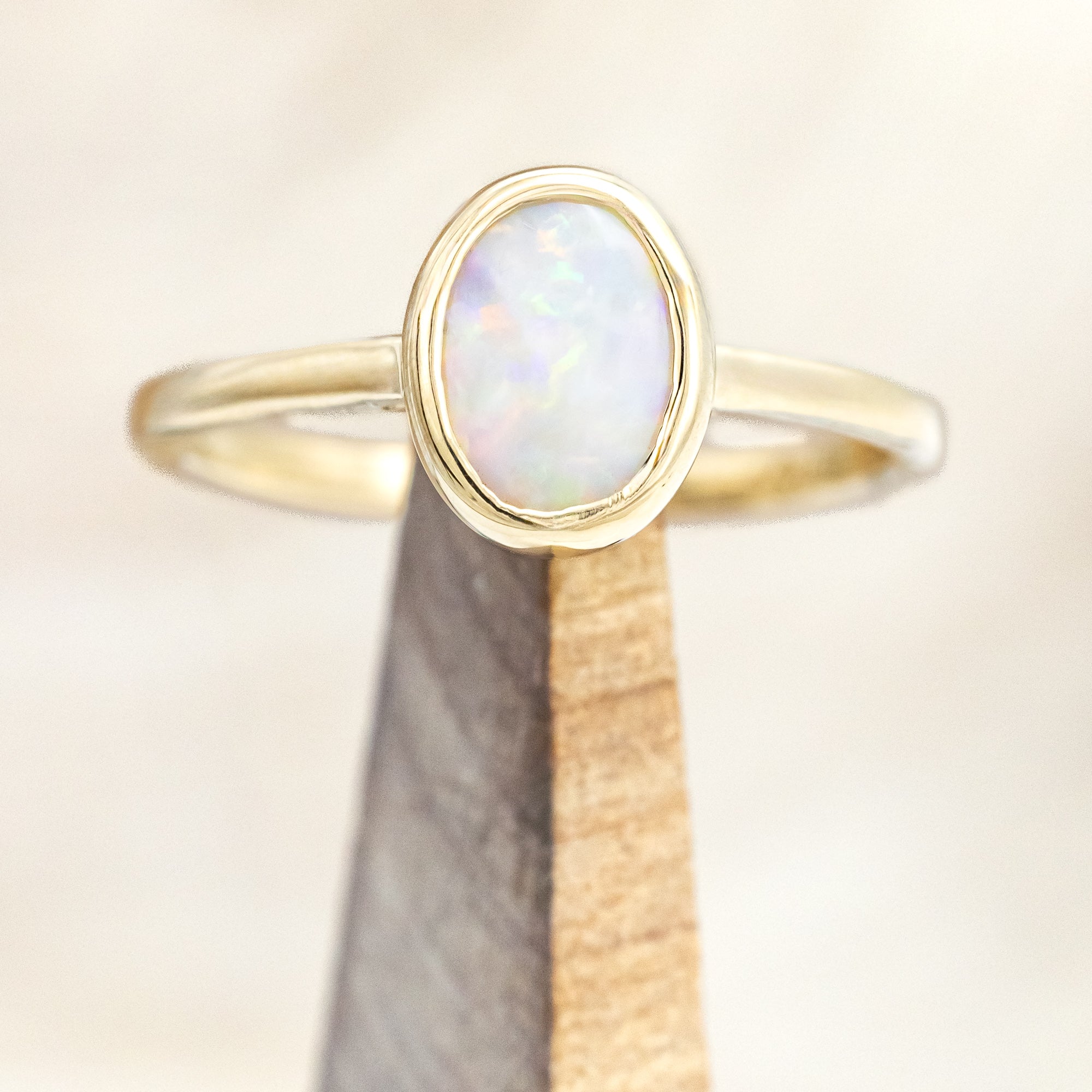 Gold ring with an opal center stone on a neutral background