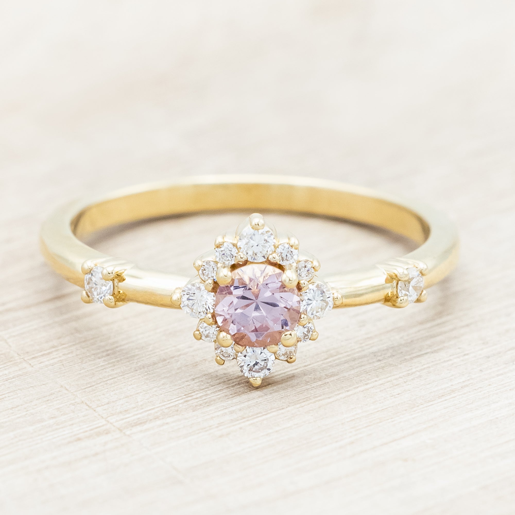 Gold ring with a dragon garnet and diamond accents on a light wooden surface