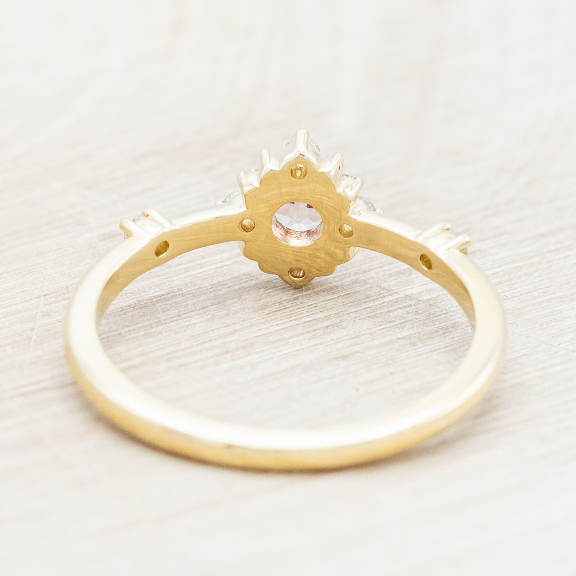 Gold ring with a dragon garnet and diamond accents on a light wooden surface