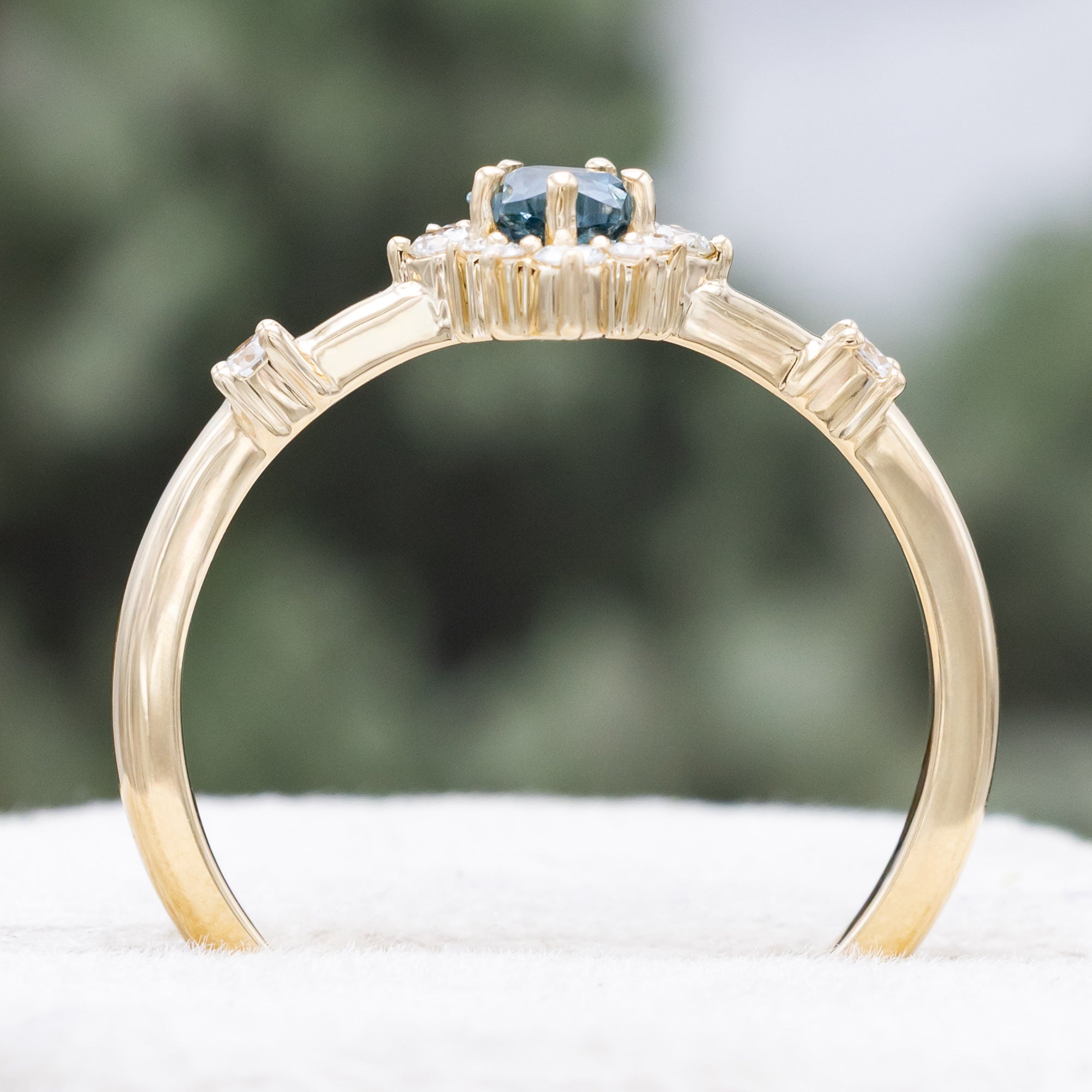 Gold ring with a blue star-shaped sapphire and diamond accents on a blurred green background