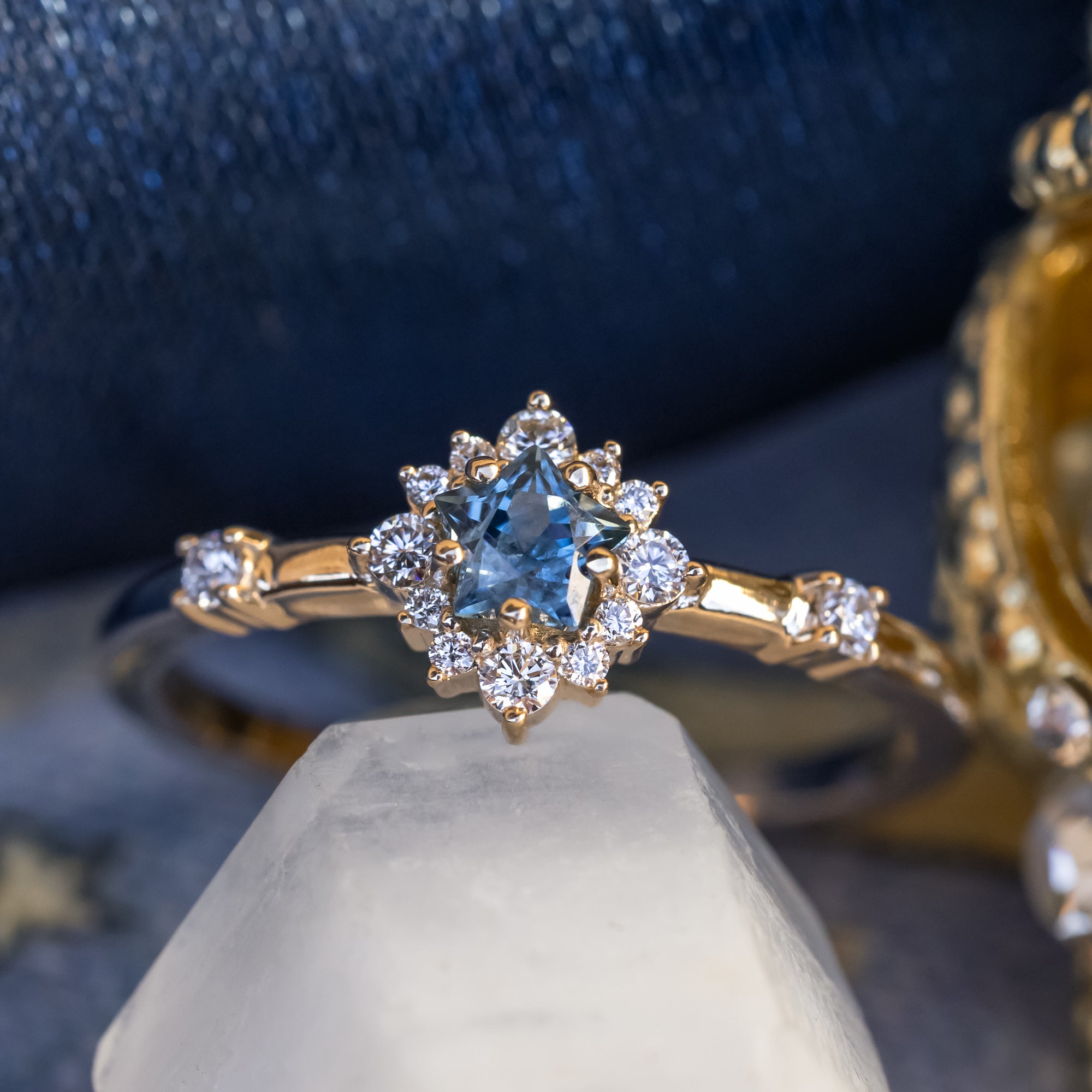 Gold ring with a star-shaped blue sapphire on a white stand against a dark background