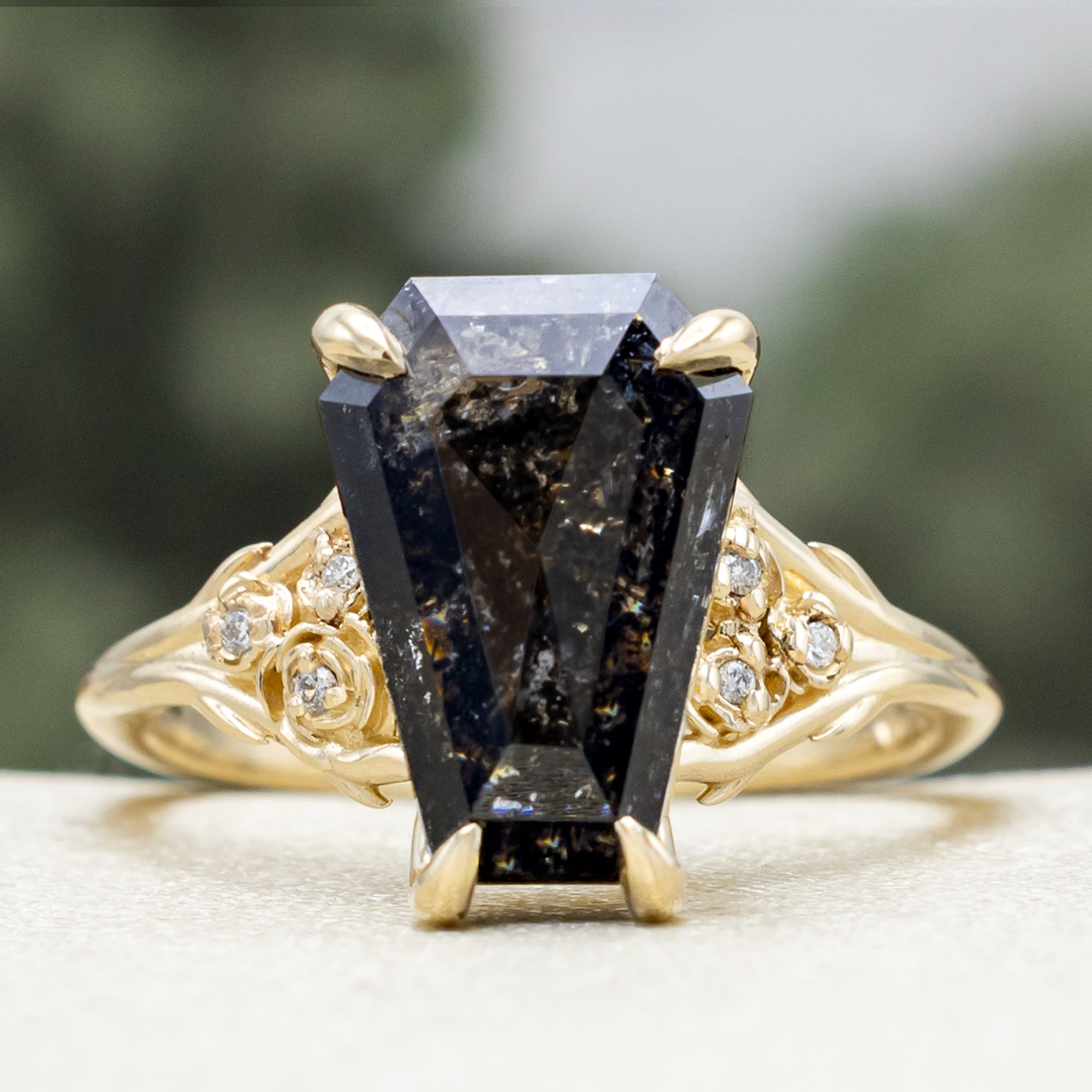Gold ring with a salt & pepper diamond and diamond accents on a blurred background
