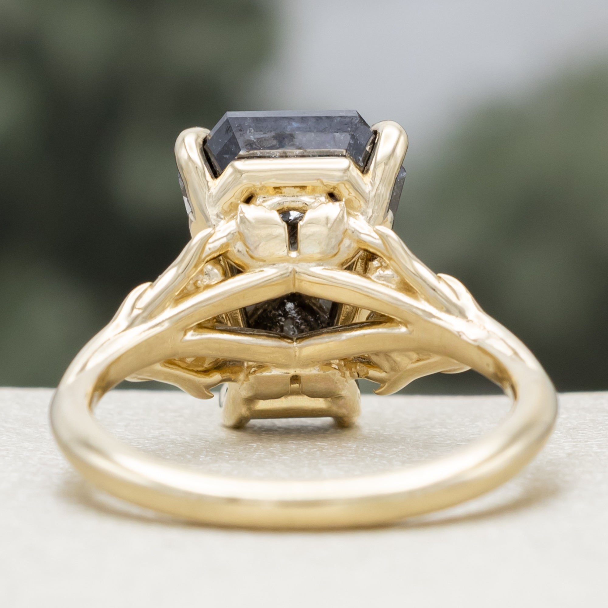 Gold ring with a salt & pepper diamond and diamond accents on a blurred background