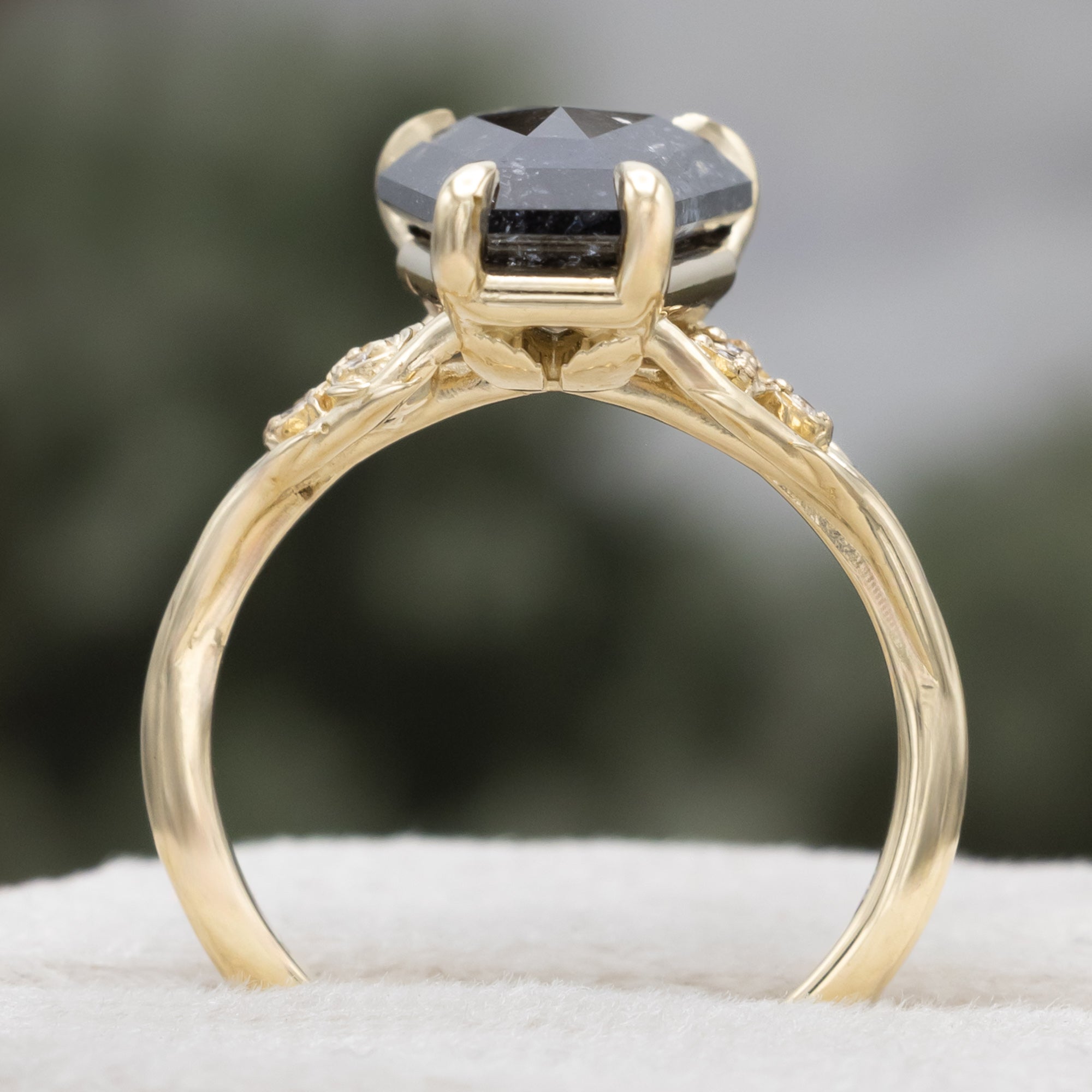Gold ring with a salt & pepper diamond and diamond accents on a blurred background