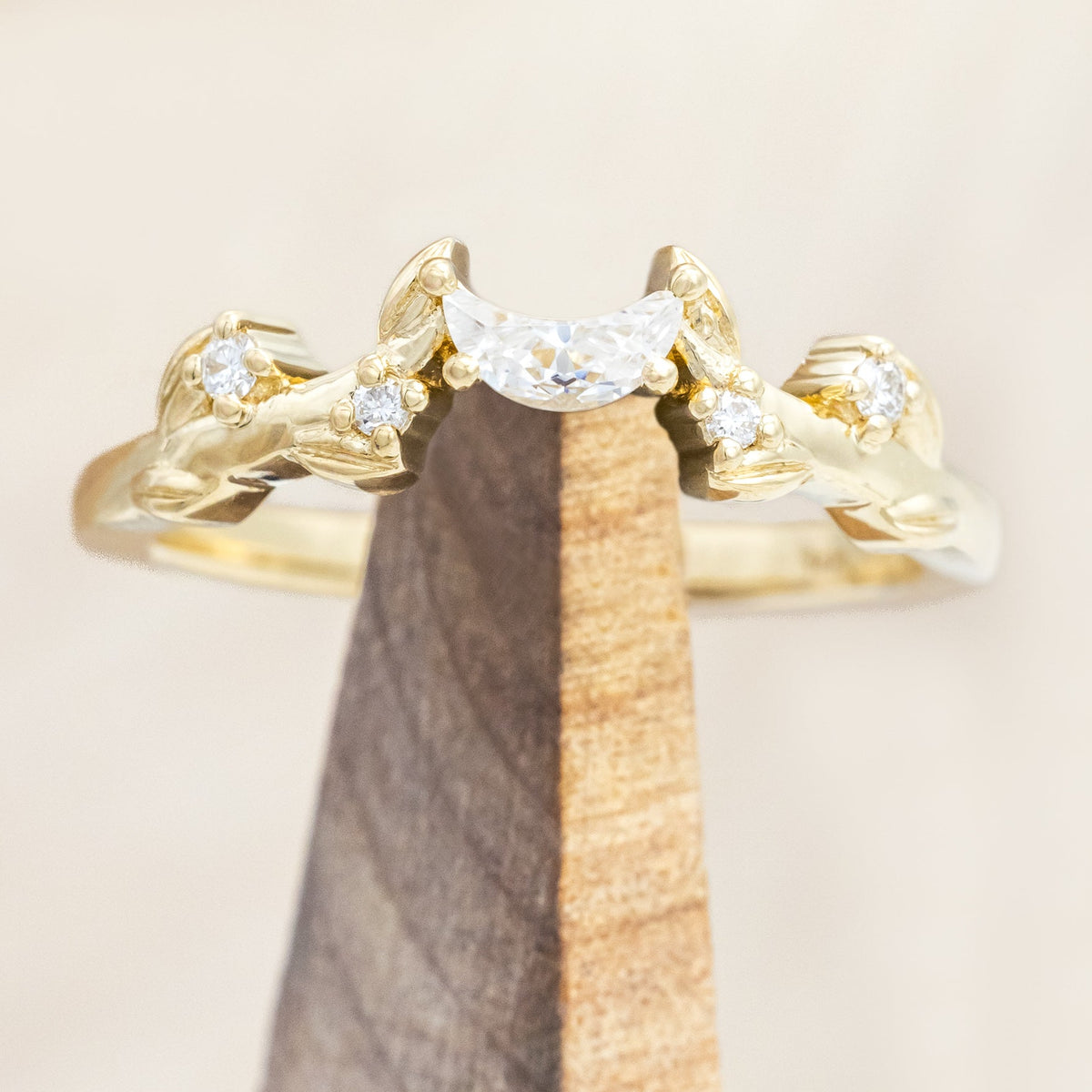 14K gold ring with diamond & moissanite accents on a wooden stand against a beige background