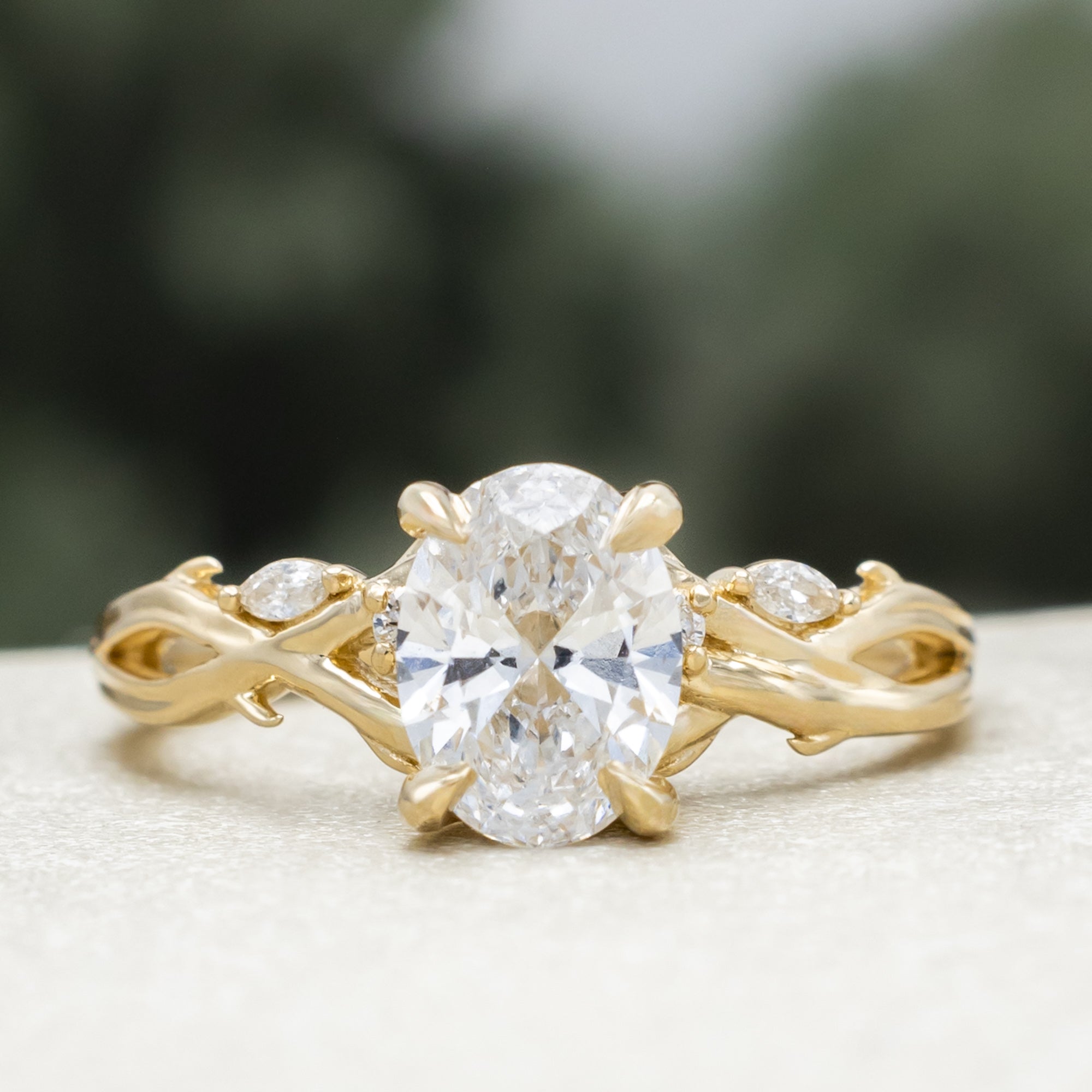 14K gold engagement ring with oval lab-grown diamond and accents against a blurred background