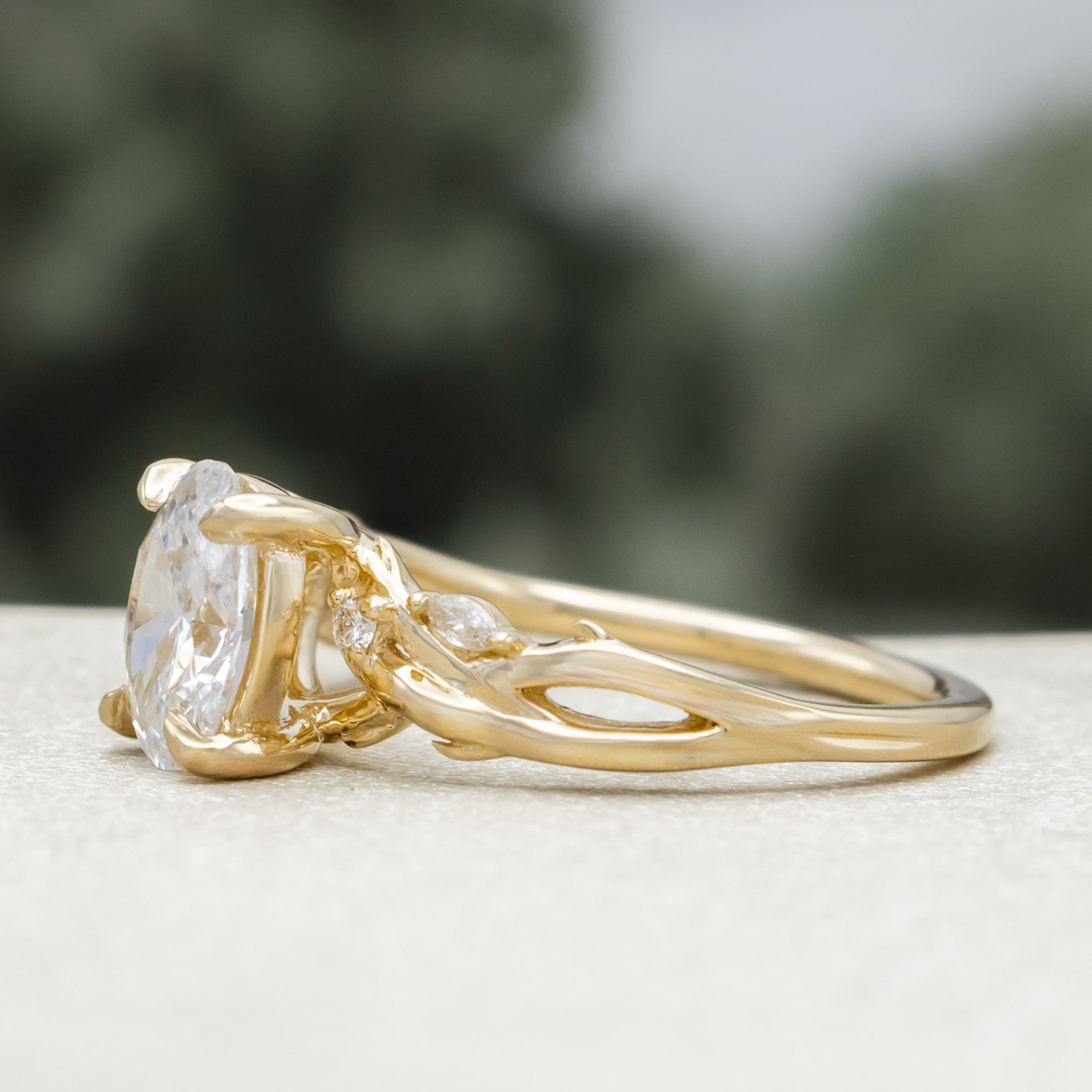 14K gold engagement ring with oval lab-grown diamond and accents against a blurred background