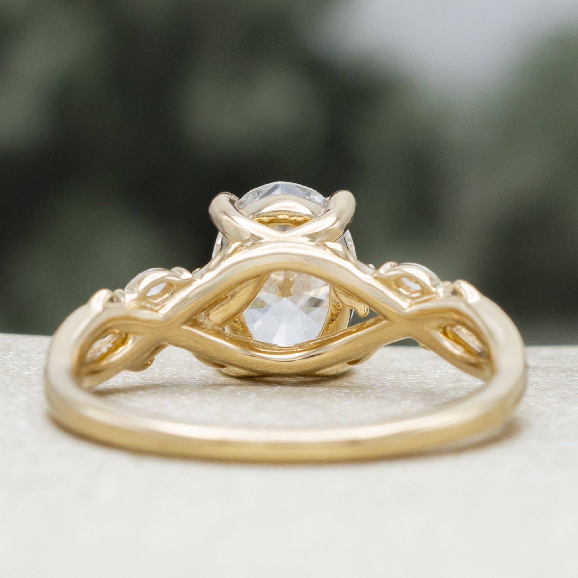14K gold engagement ring with oval lab-grown diamond and accents against a blurred background