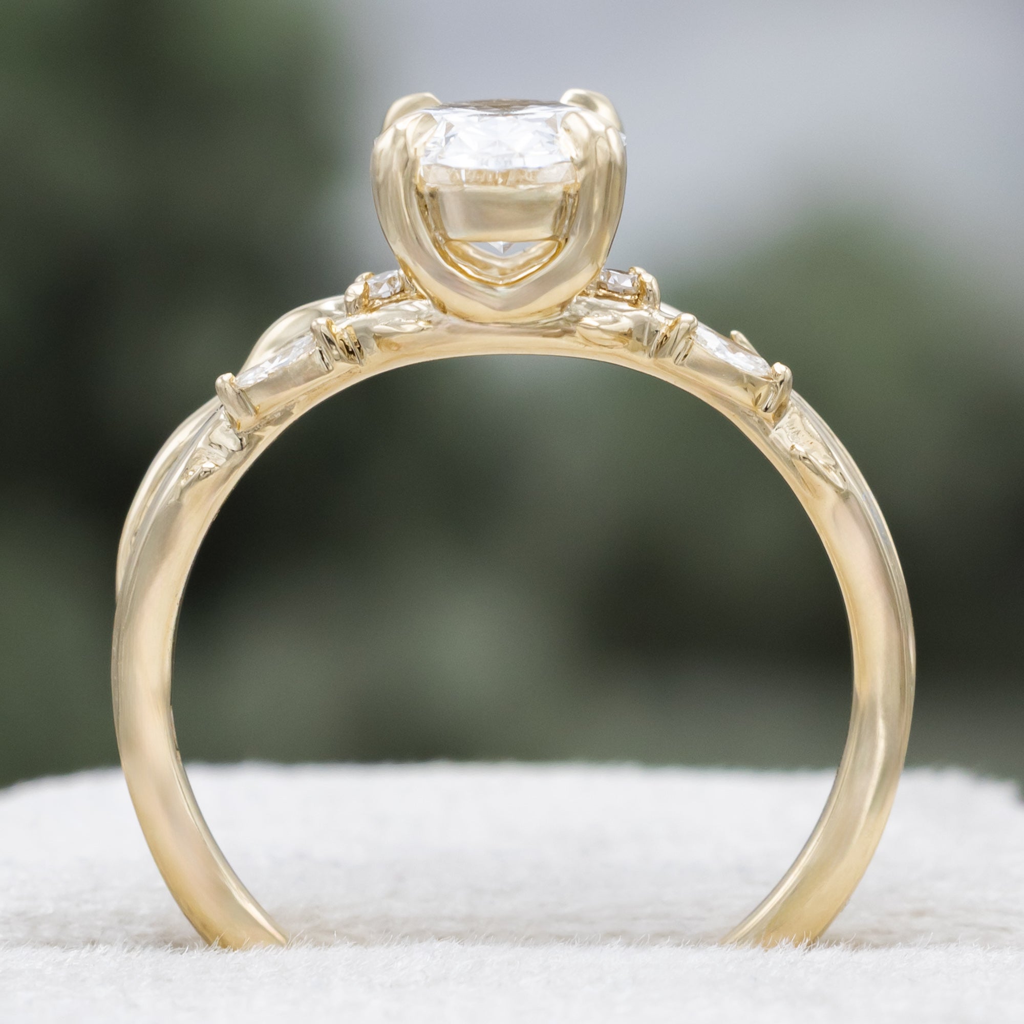 14K gold engagement ring with oval lab-grown diamond and accents against a blurred background
