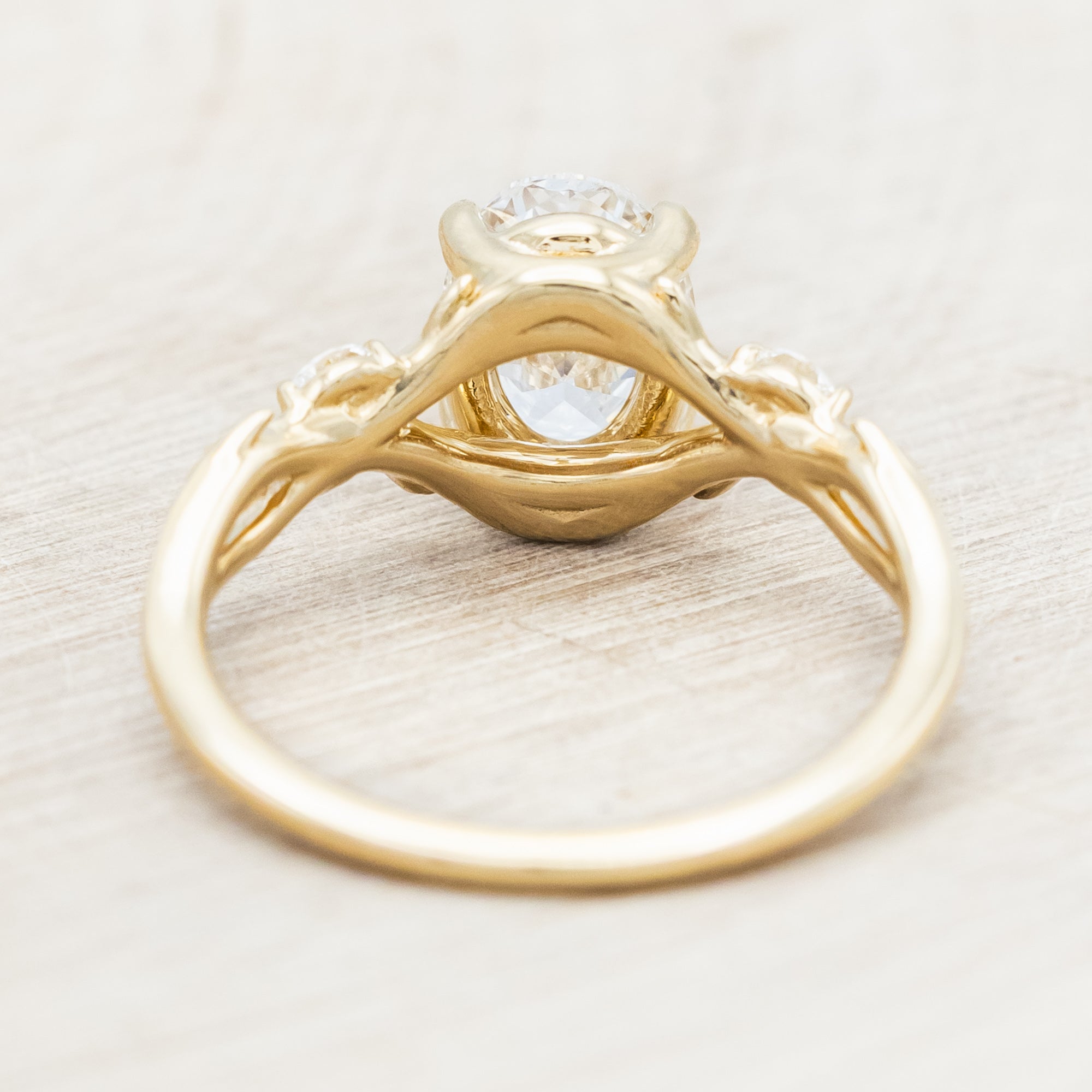 14K gold engagement ring with oval lab-grown diamond and accents against beige background