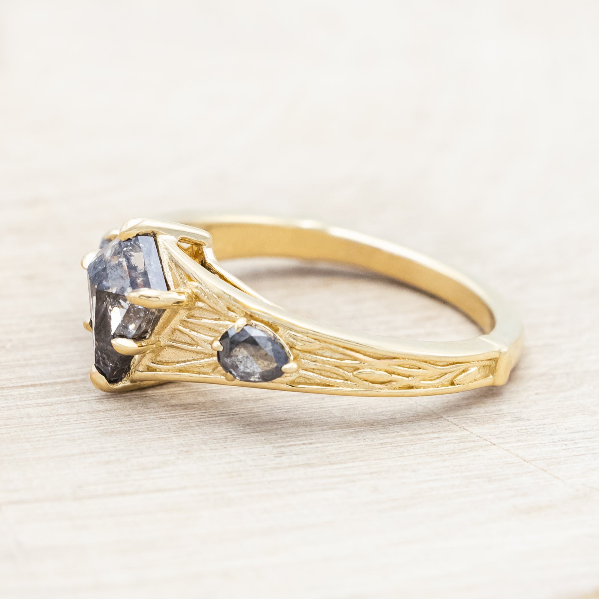 14K gold ring with salt & pepper diamond on a wooden surface