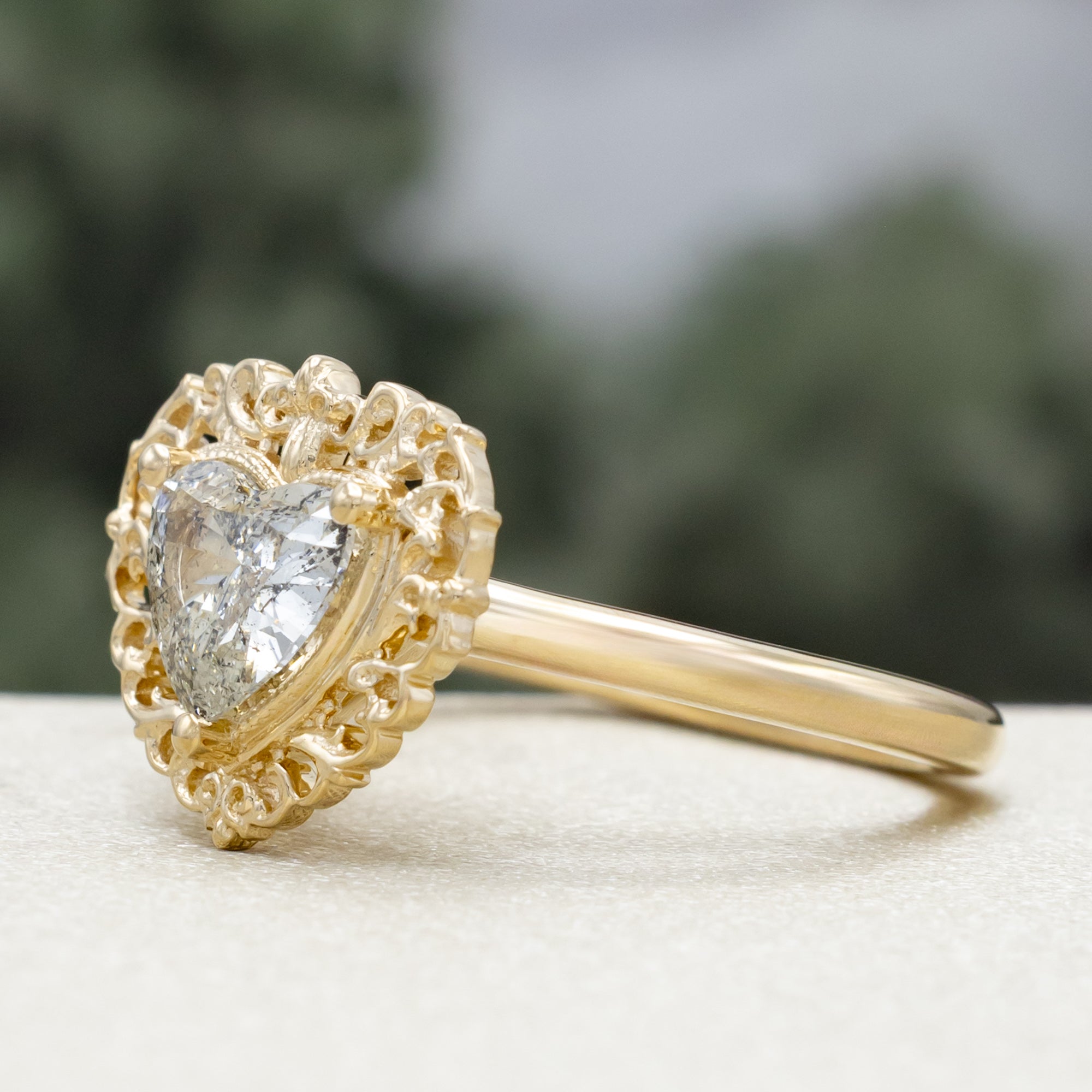Gold ring with a heart-shaped salt & pepper diamond on a blurred background
