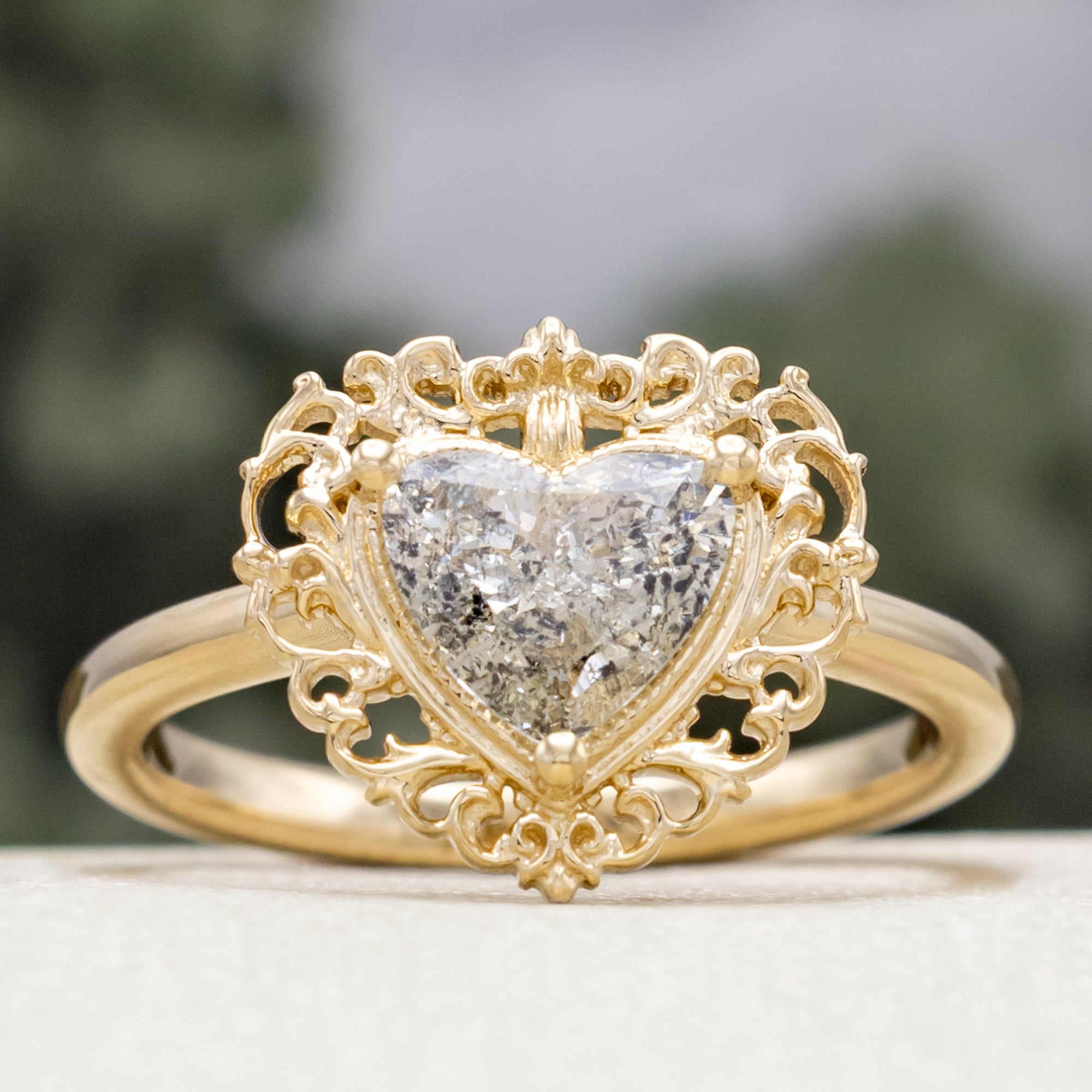 Gold ring with a heart-shaped salt & pepper diamond on a blurred background