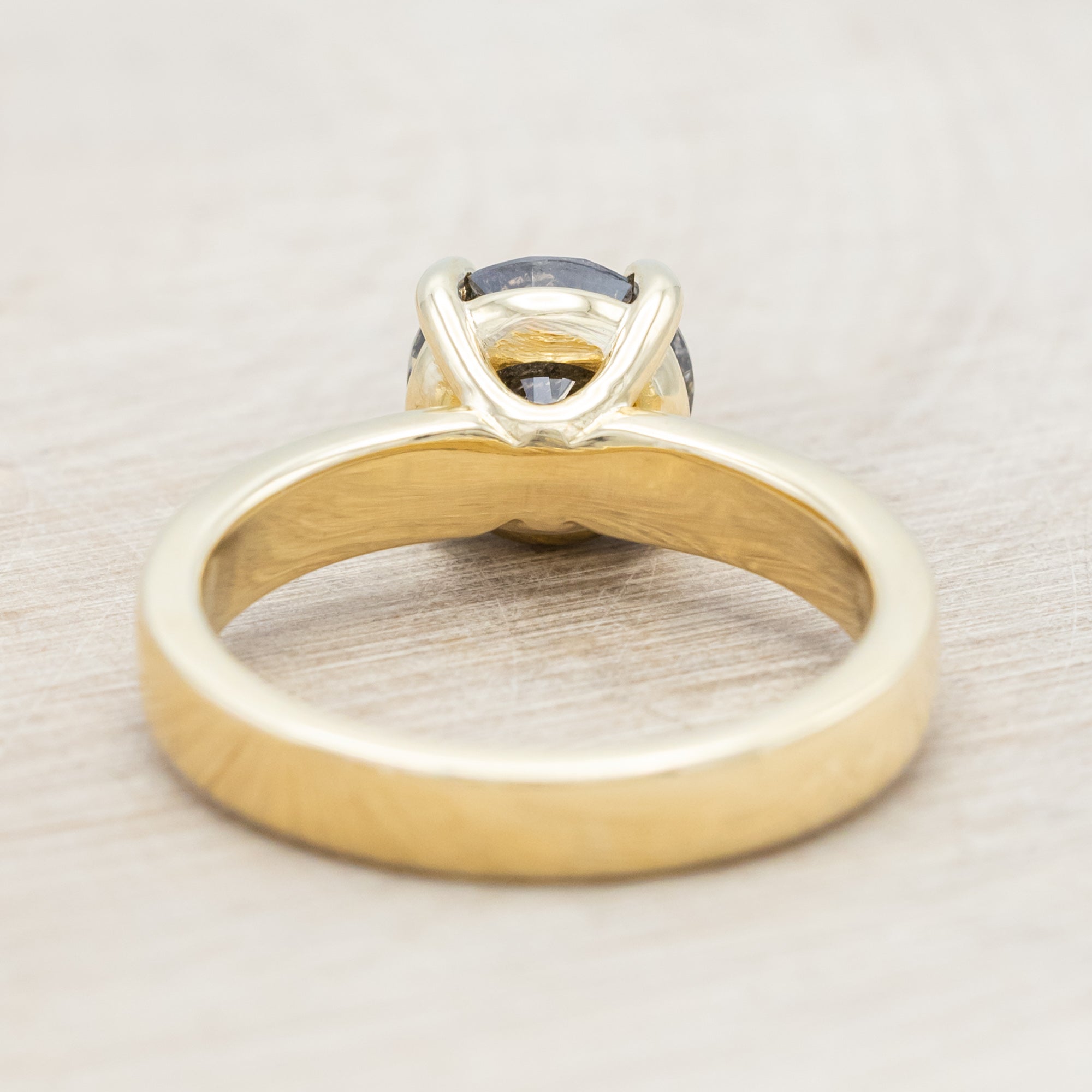 Wide 14K gold ring with a salt & pepper diamond on a beige background
