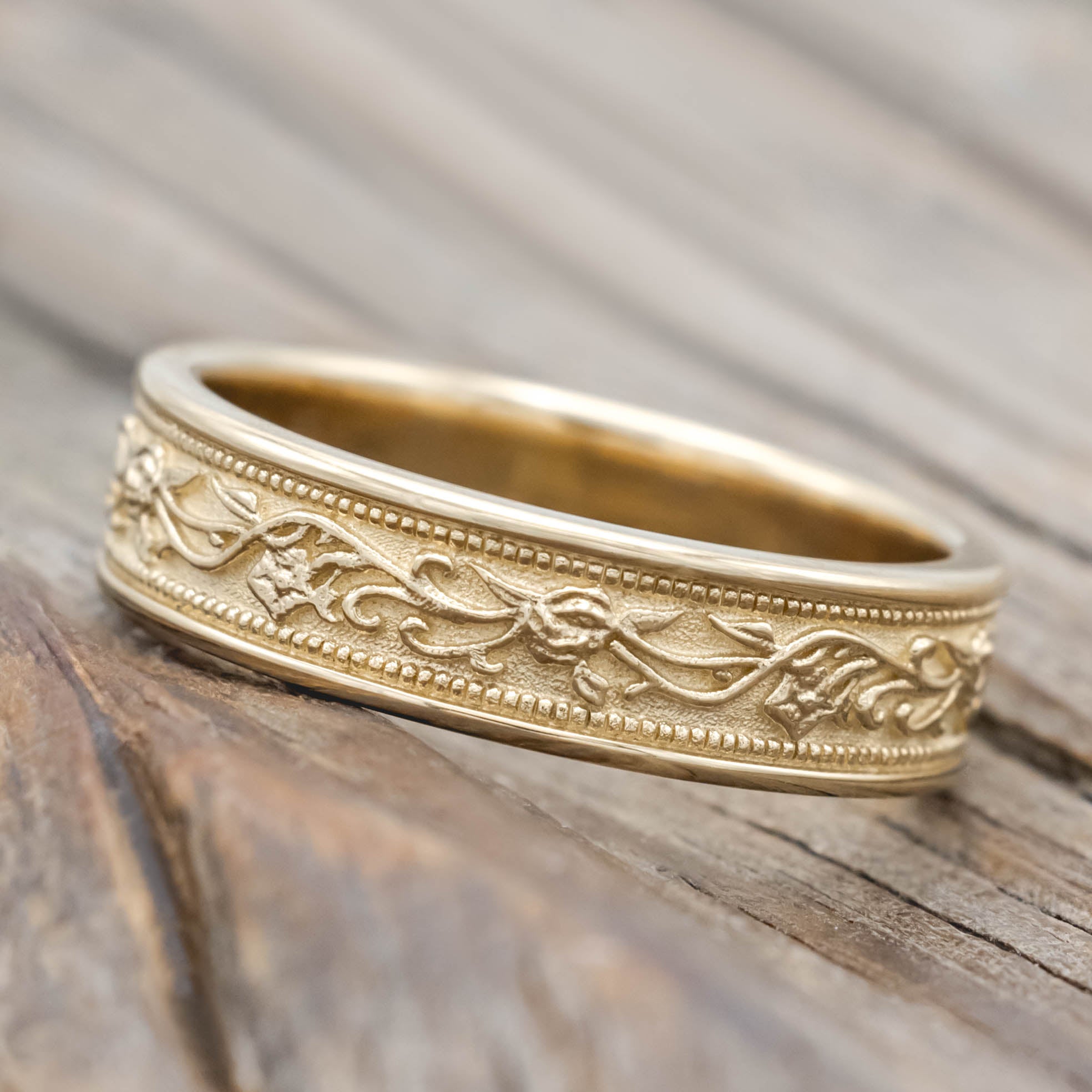 Gold ring with intricate floral designs on a wooden surface