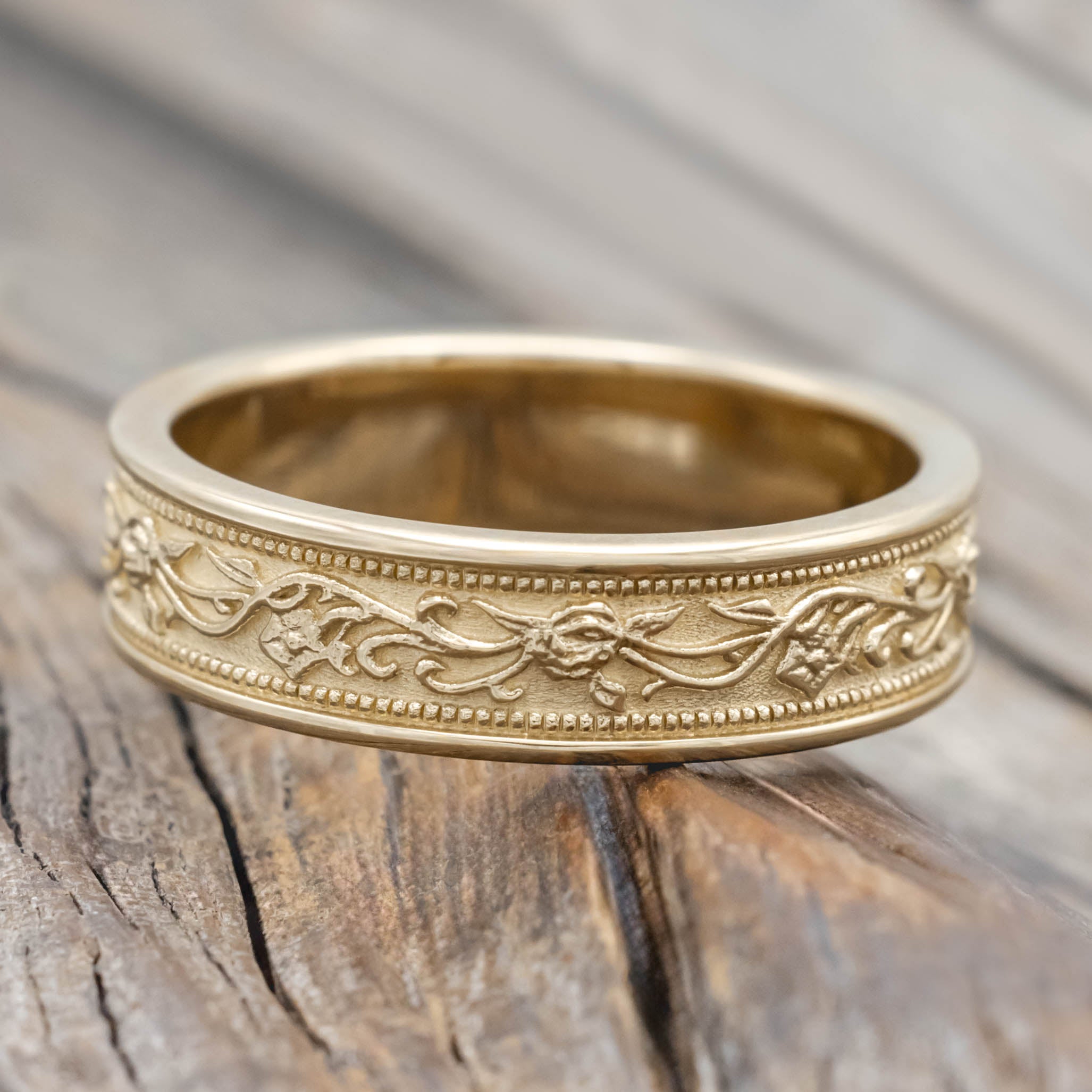 Gold ring with intricate floral designs on a wooden surface