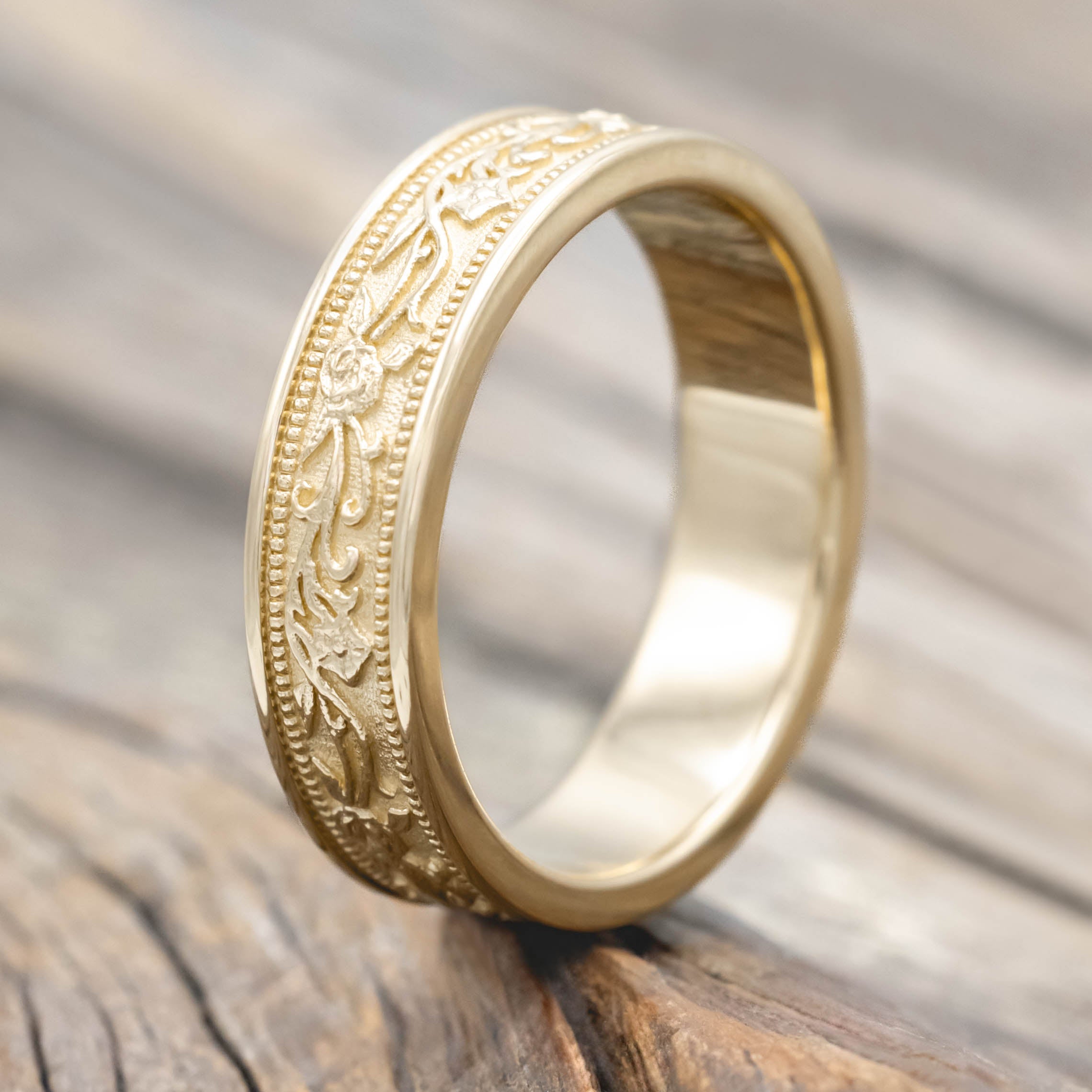 Gold ring with intricate floral designs on a wooden surface