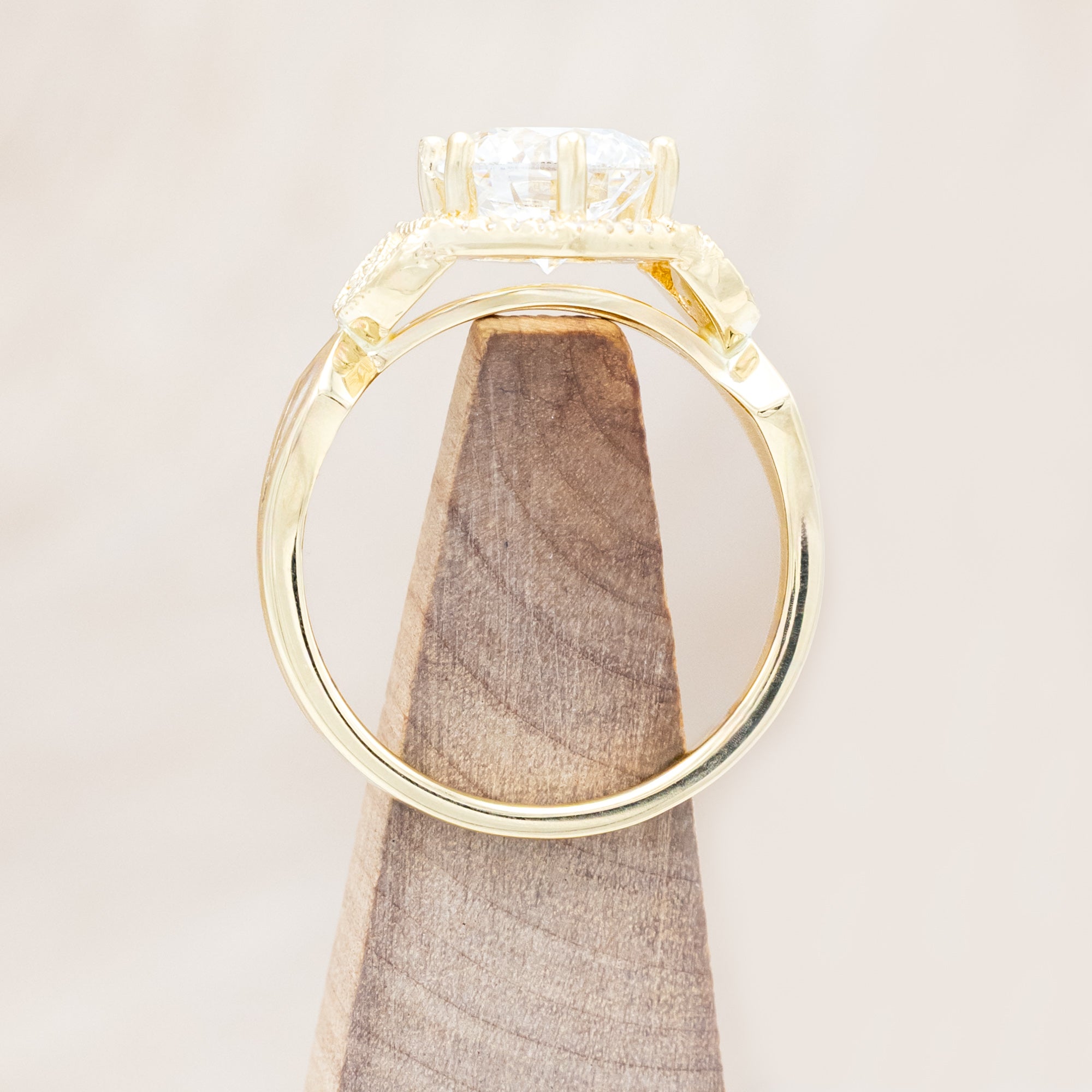 Yellow gold ring with a lab-grown diamond and diamond accents on a beige background
