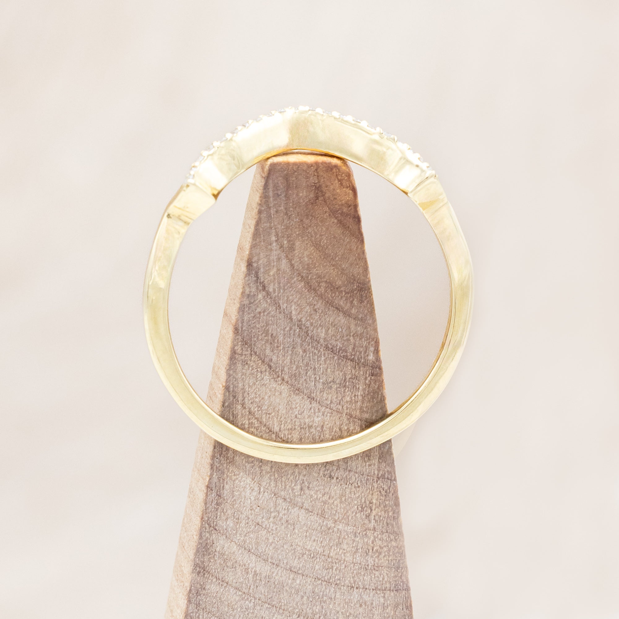 Yellow gold ring with diamond accents on a beige background