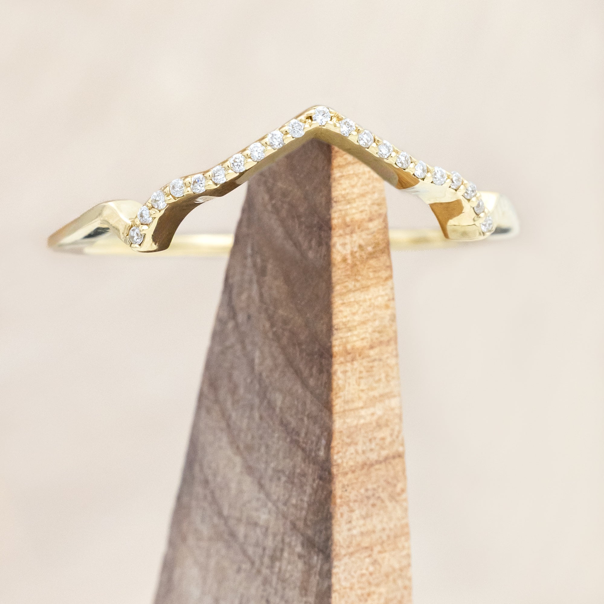 Yellow gold ring with diamond accents on a beige background