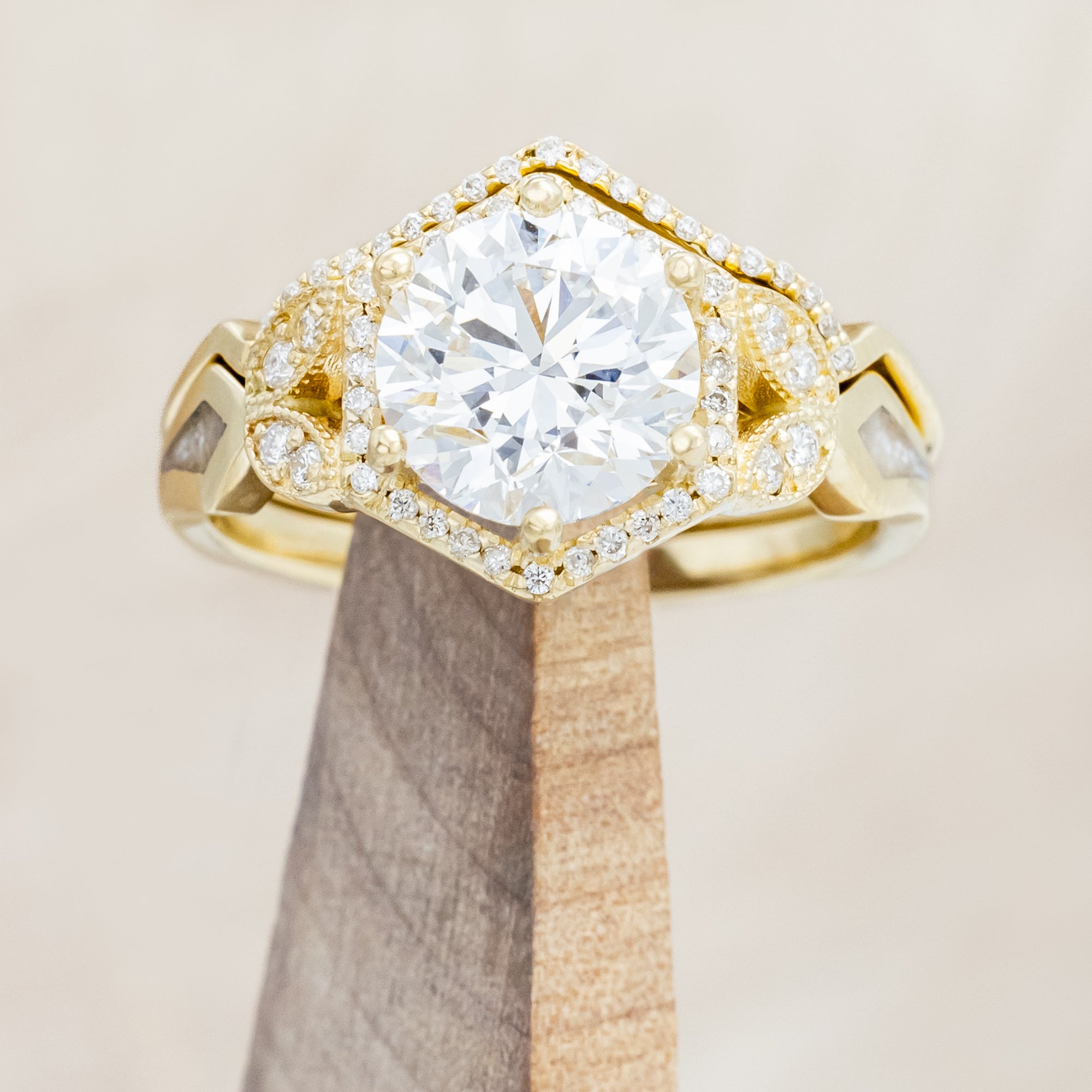 Yellow gold ring with a lab-grown diamond and diamond accents with diamond tracer on a beige background