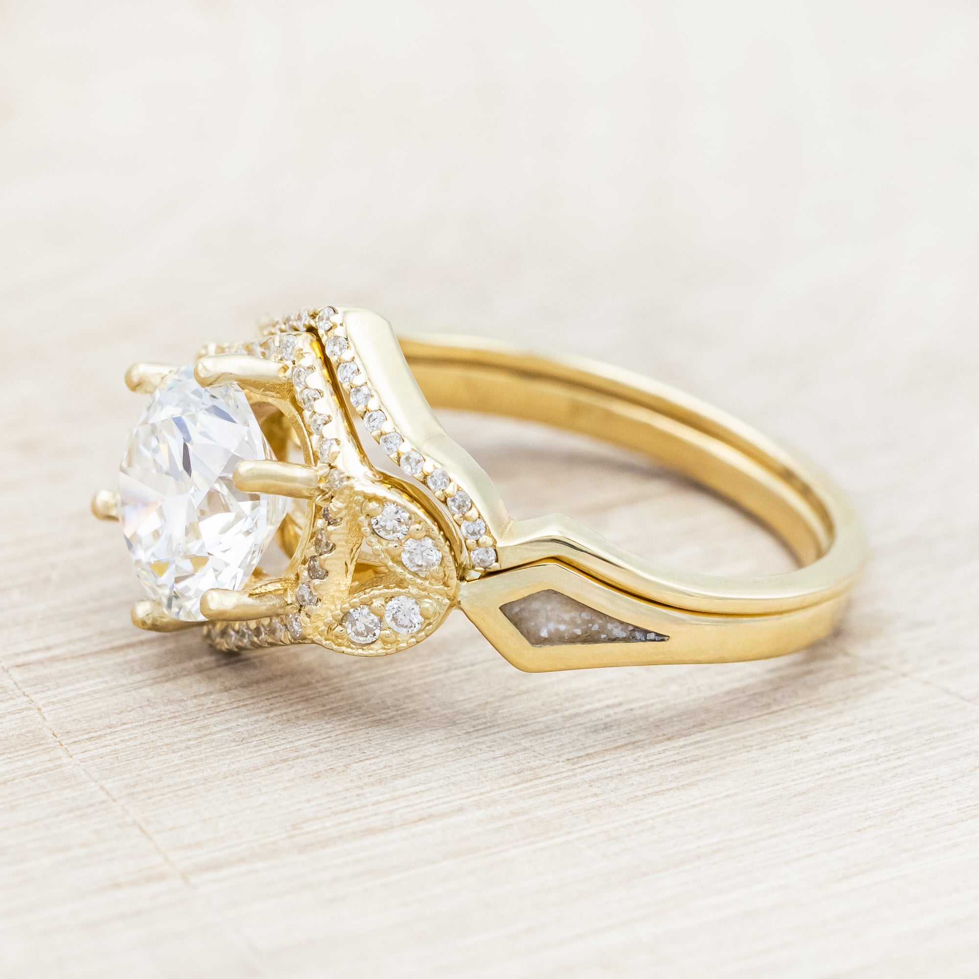 Yellow gold ring with a lab-grown diamond and diamond accents with diamond tracer on a beige background