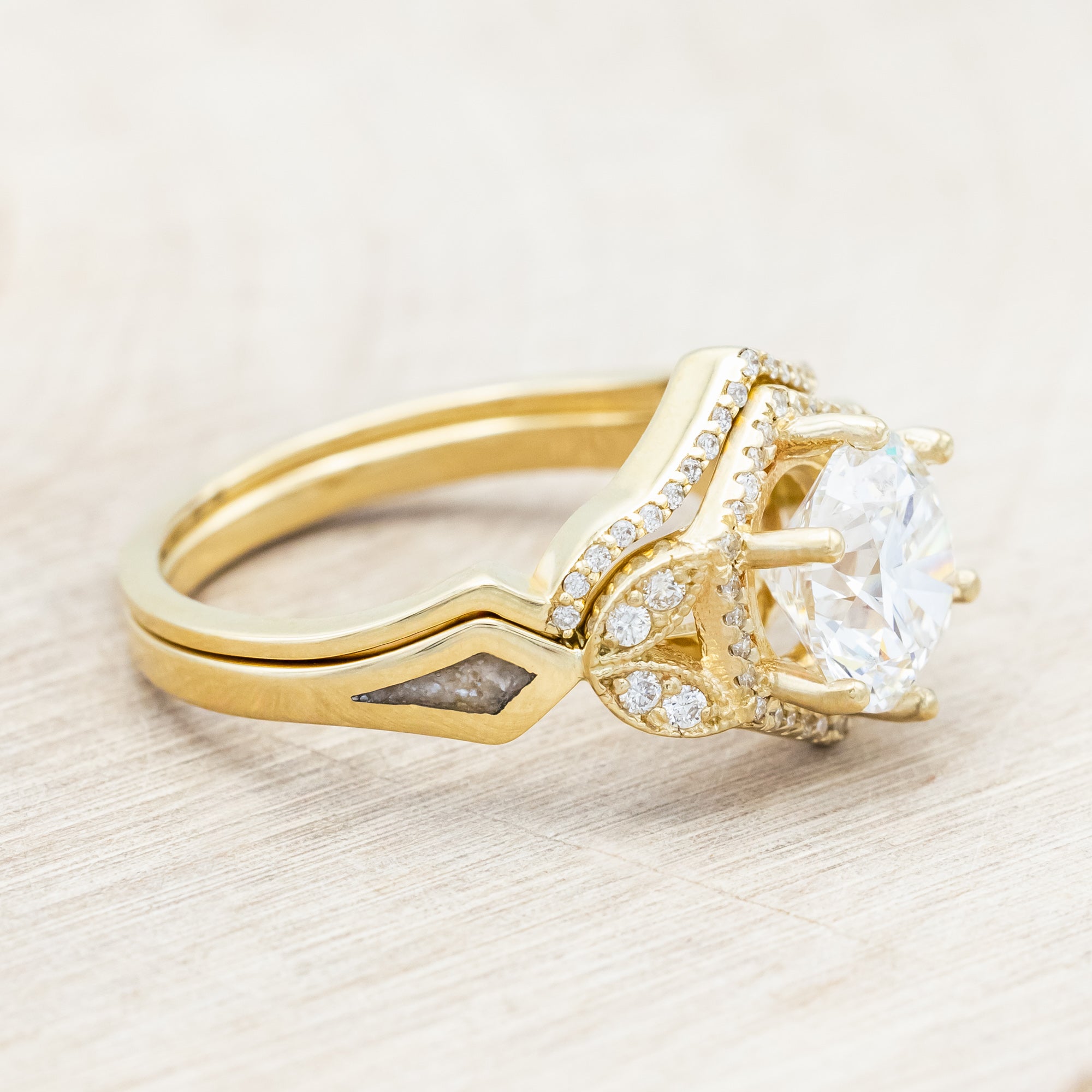 Yellow gold ring with a lab-grown diamond and diamond accents with diamond tracer on a beige background