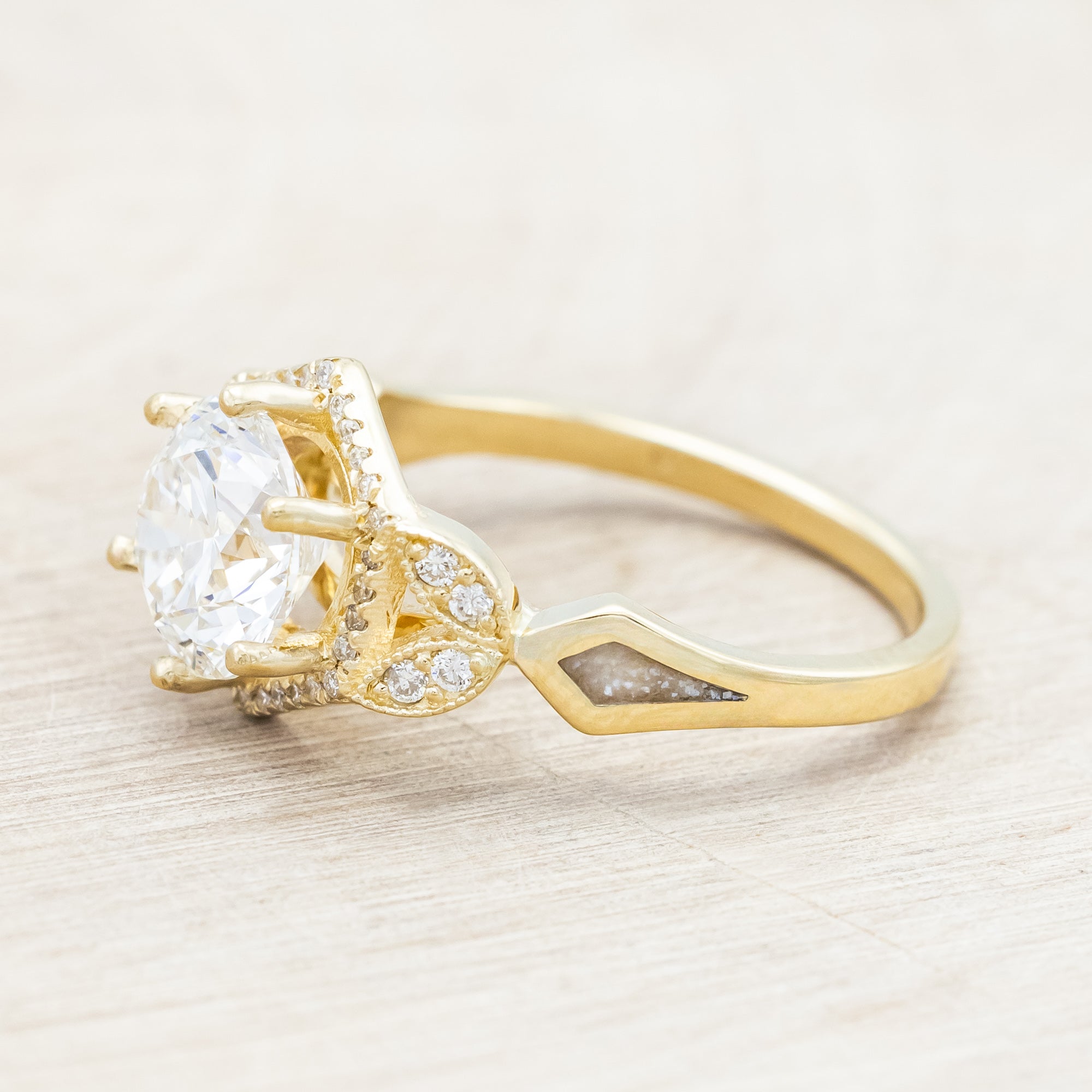 Yellow gold ring with a lab-grown diamond and diamond accents on a beige background