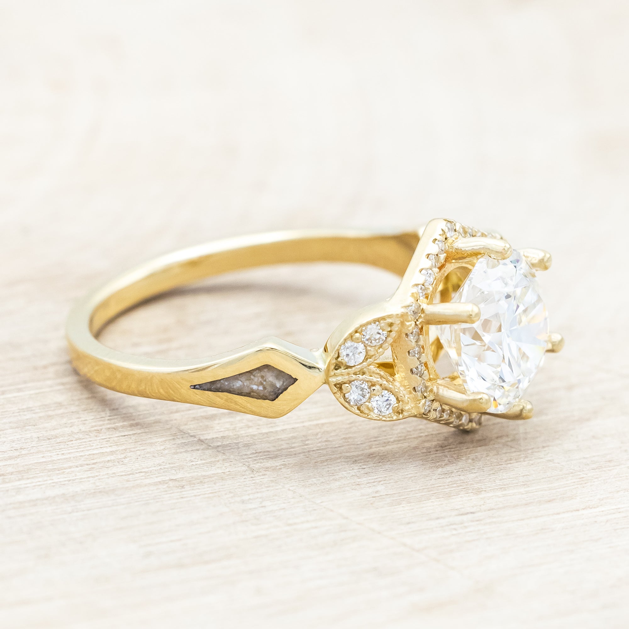Yellow gold ring with a lab-grown diamond and diamond accents on a beige background
